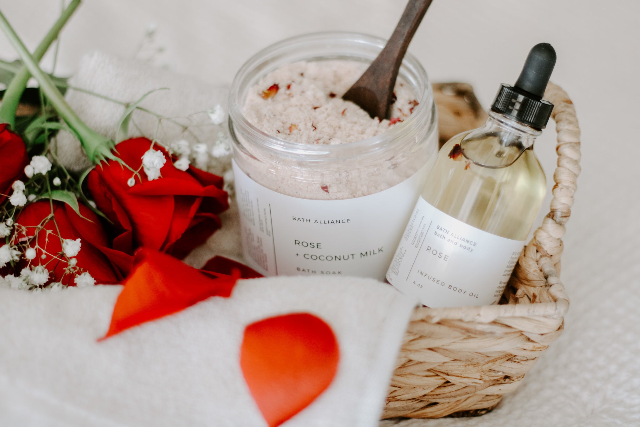 A jar of Rose + Coconut Milk Bath Soak featuring dried rose petals and powdered coconut milk, perfect for a relaxing bath experience.