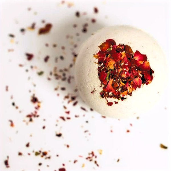 A vibrant Rose Petal Bath Bomb with rose petals and essential oils, fizzing in a bath of warm water, creating a luxurious spa experience.