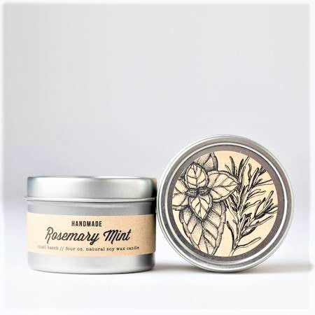 A 4oz steel travel tin candle filled with a light green wax, featuring a label that reads 'Rosemary Mint', surrounded by fresh rosemary and mint leaves.