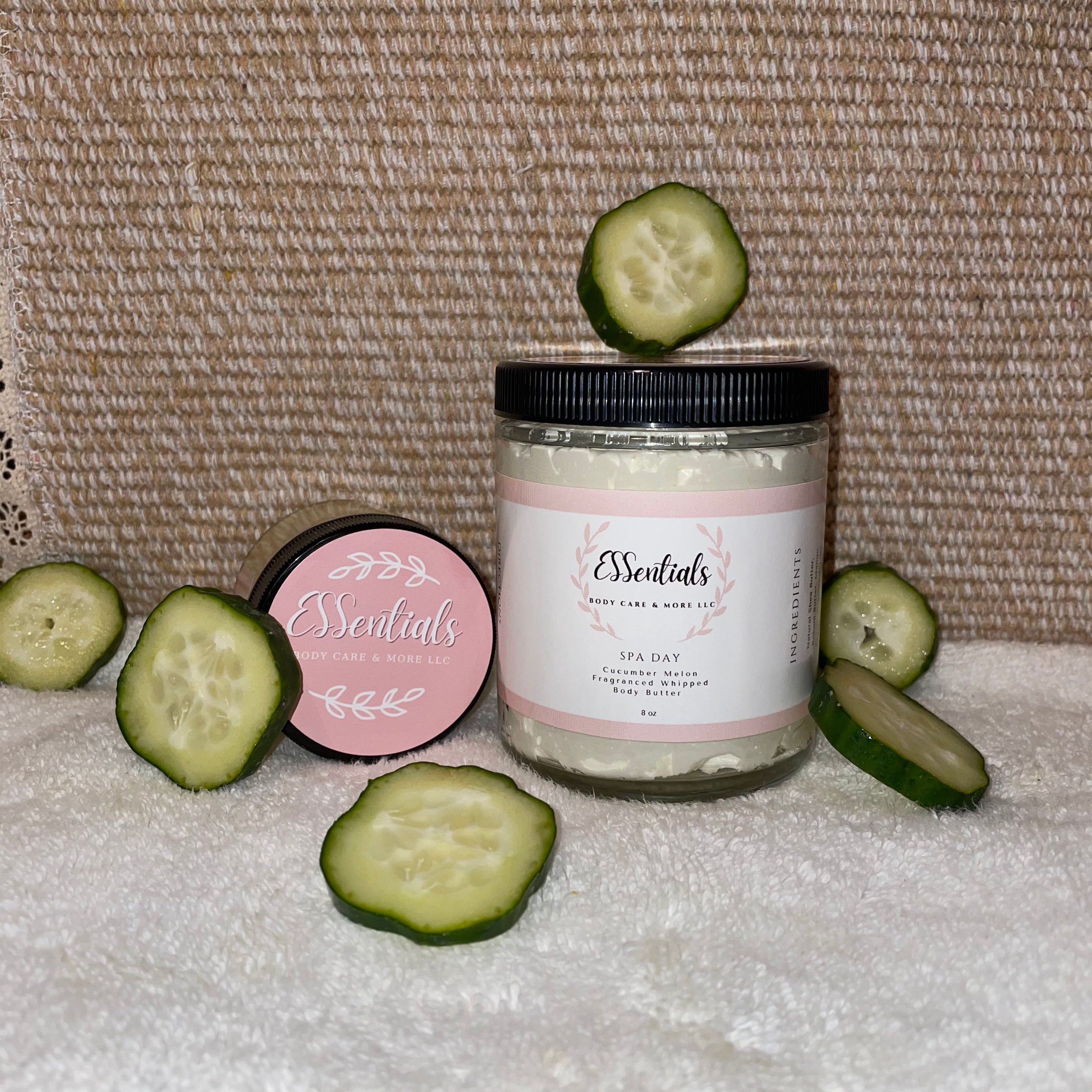 A luxurious jar of Spa Day body butter with cucumber melon fragrance, surrounded by natural ingredients like shea butter and coconut oil.