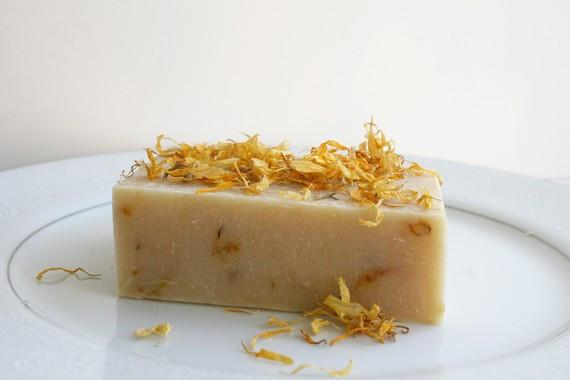 A vibrant handmade soap bar with calendula flowers, featuring a blend of citrus and herbal scents, resembling a sunny day.