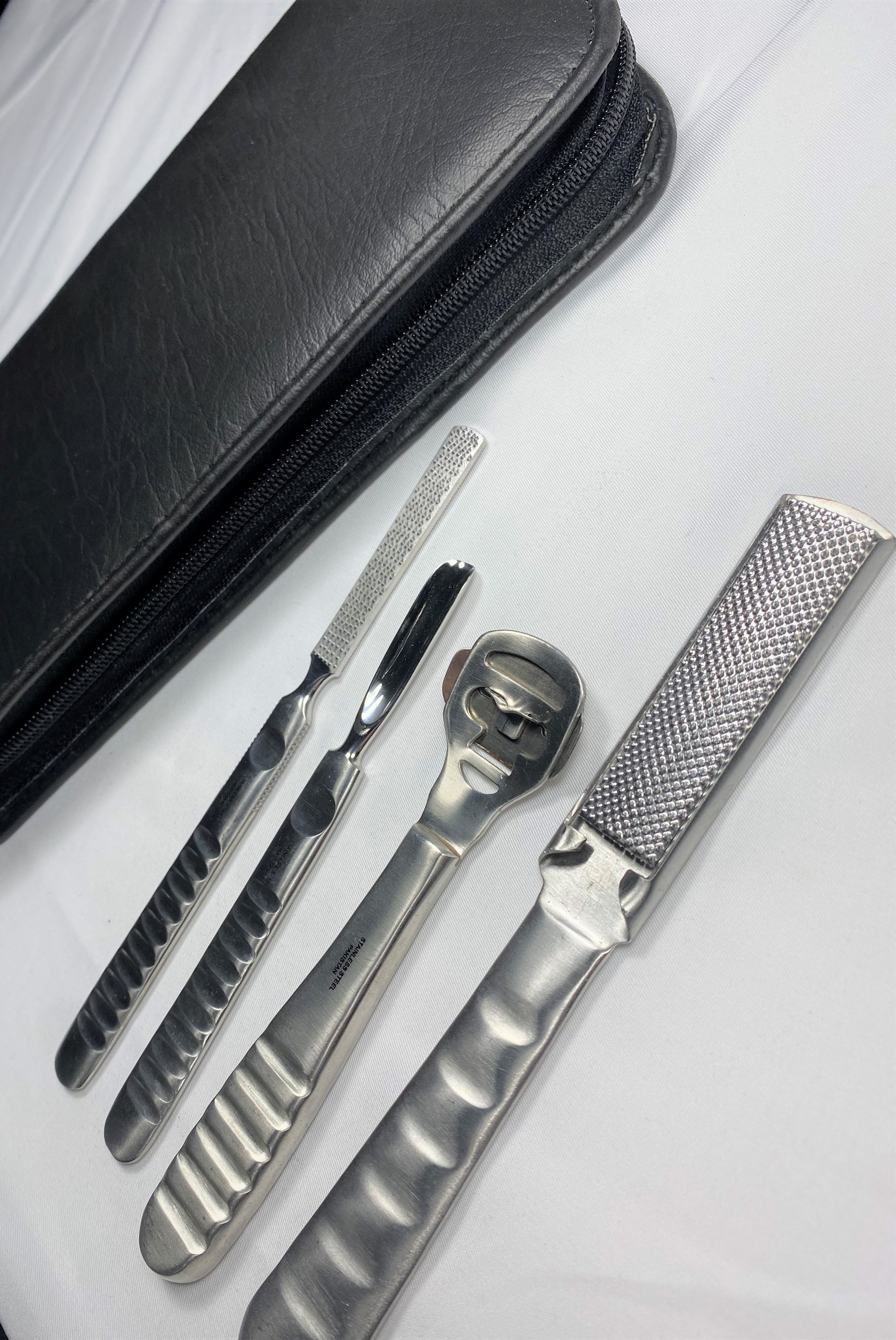 A professional-grade Stainless Steel Foot Care Set featuring four essential tools in a deluxe zipper case, showcasing their elegant satin finish.