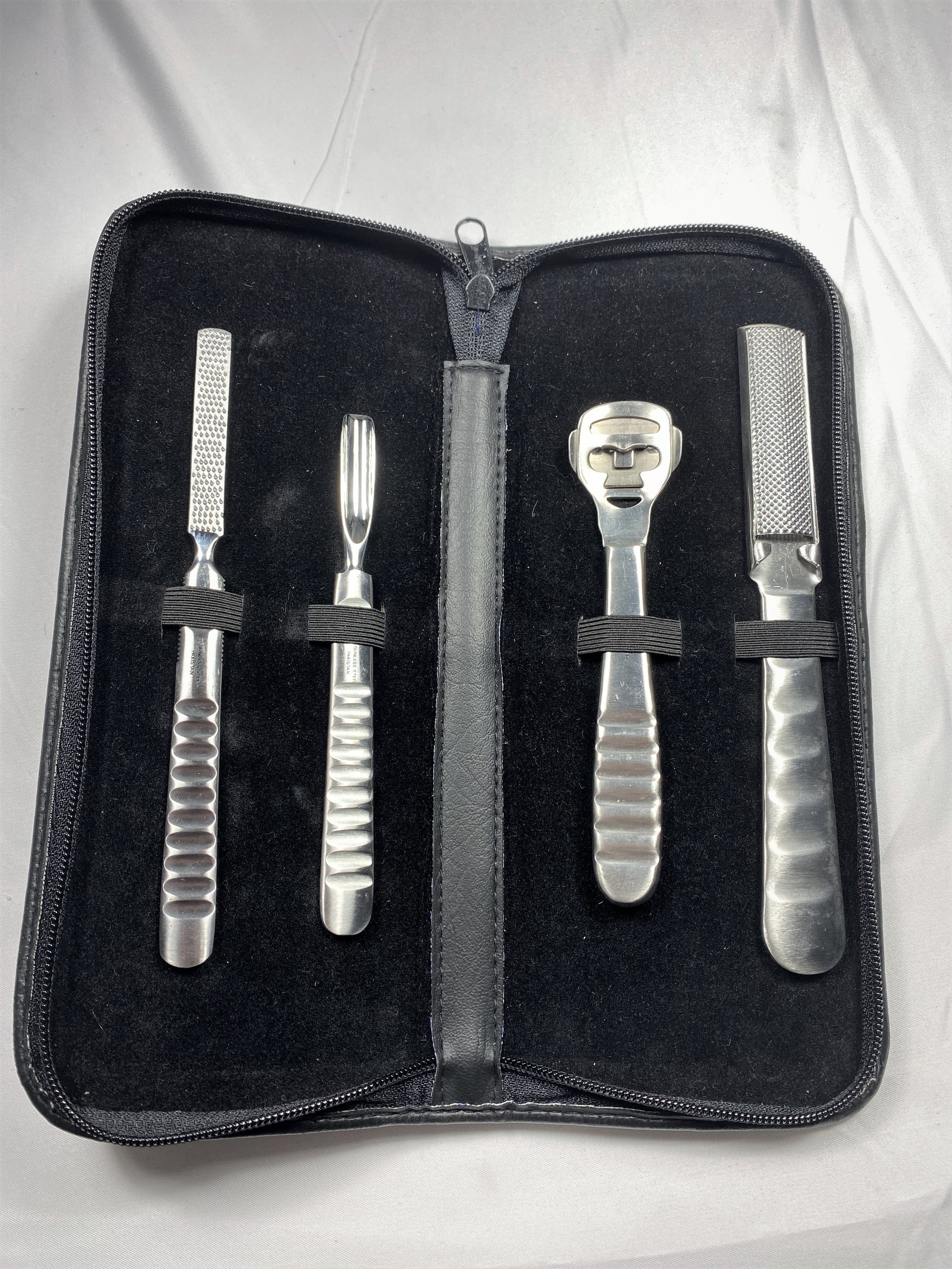 A professional-grade Stainless Steel Foot Care Set featuring four essential tools in a deluxe zipper case, showcasing their elegant satin finish.