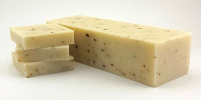 A bar of Tea Tree Mint soap with visible peppermint leaves, showcasing its natural ingredients and unique swirl patterns.