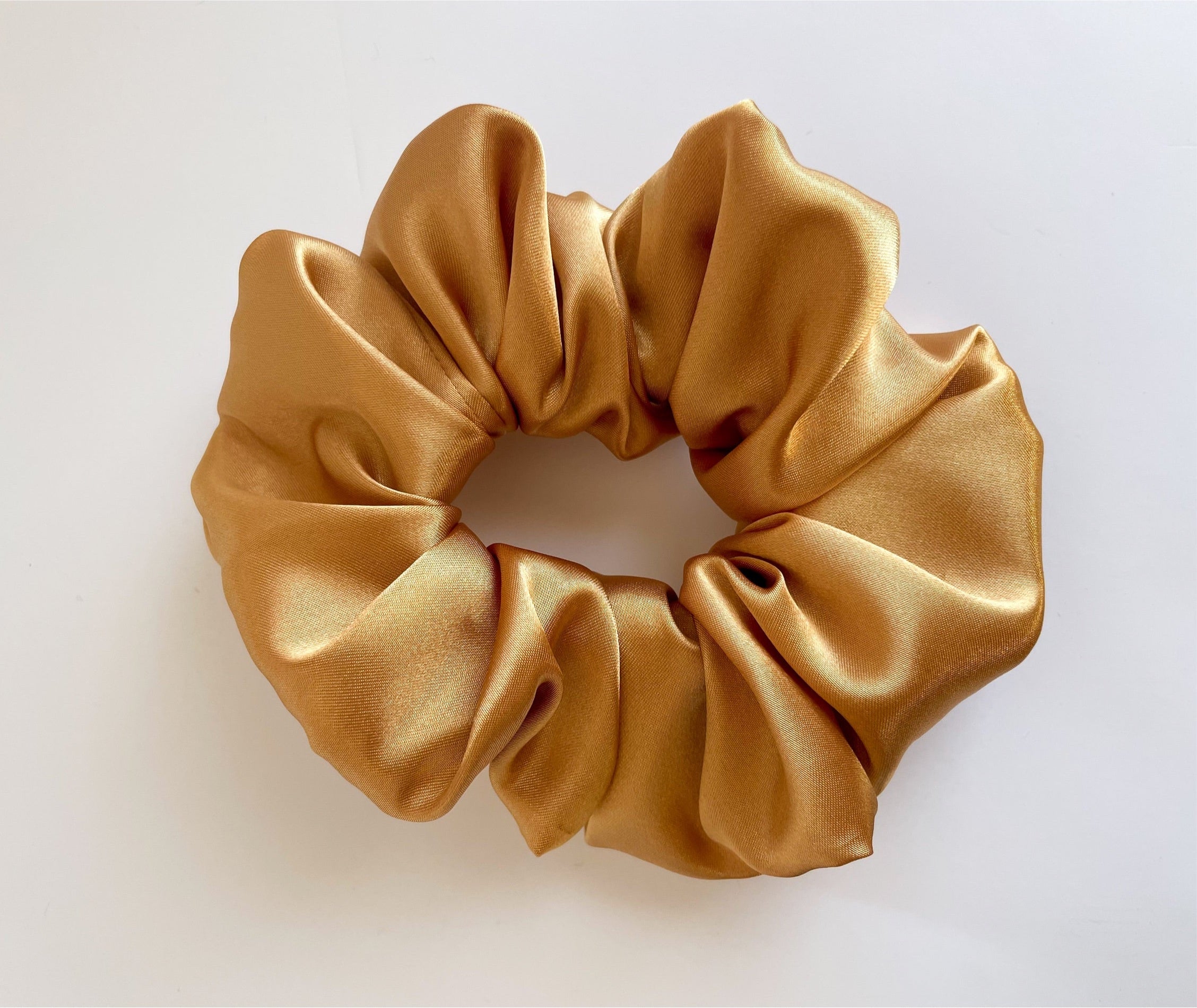 Amber satin scrunchie showcasing its luxurious texture and vibrant color, perfect for stylish hairstyles.