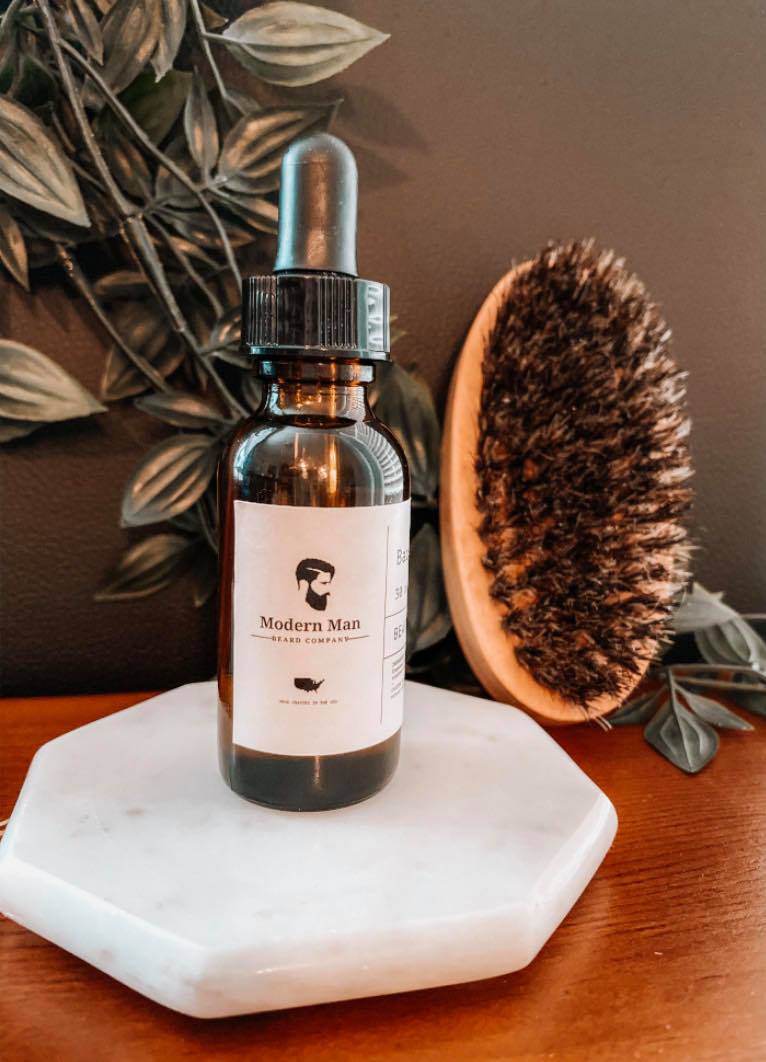 A bottle of Modern Man Beard Company Beard Growth Oil with a dropper, showcasing its premium all-natural ingredients for beard growth.