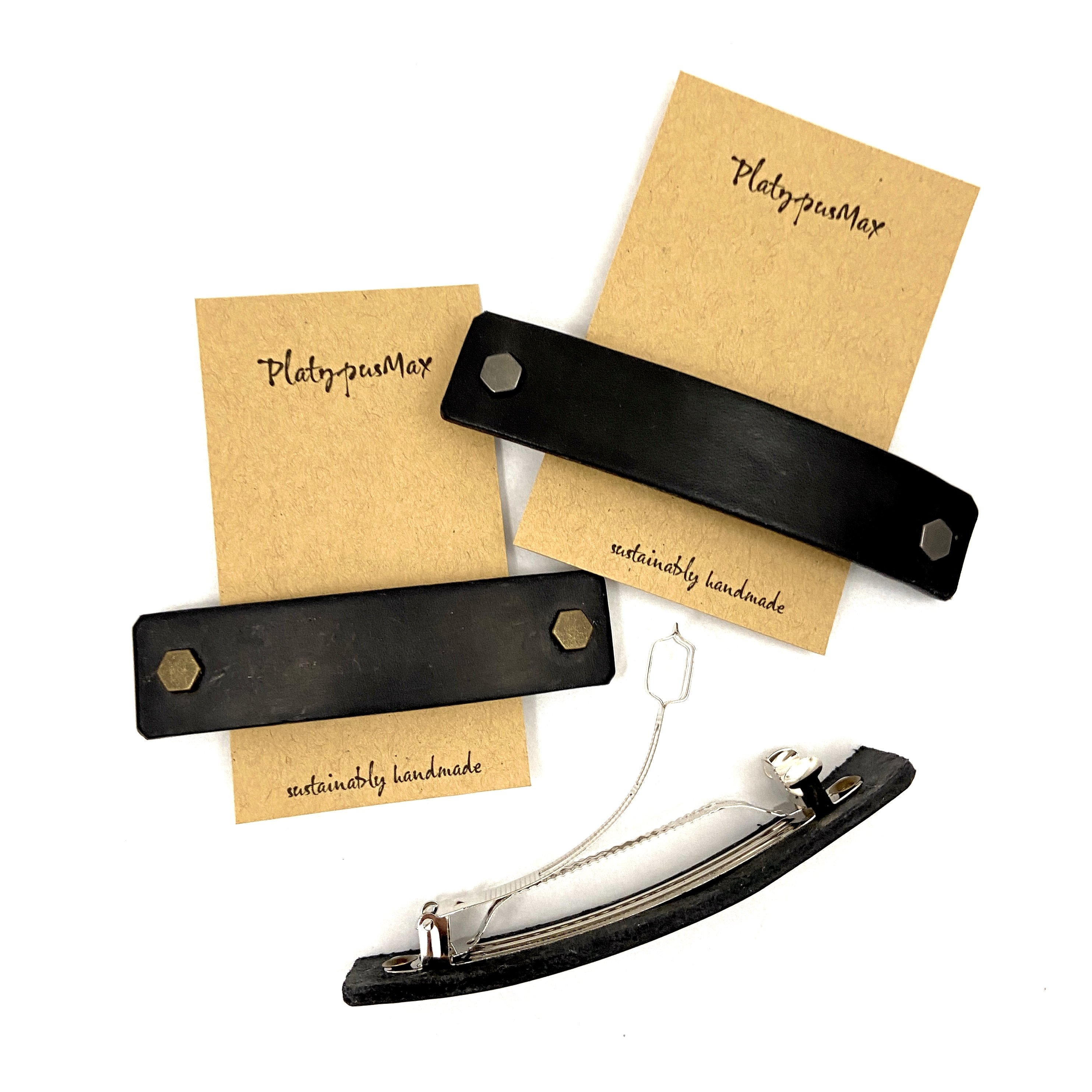 Black leather barrette with industrial hex hardware, showcasing eco-friendly design and sturdy metal clip.