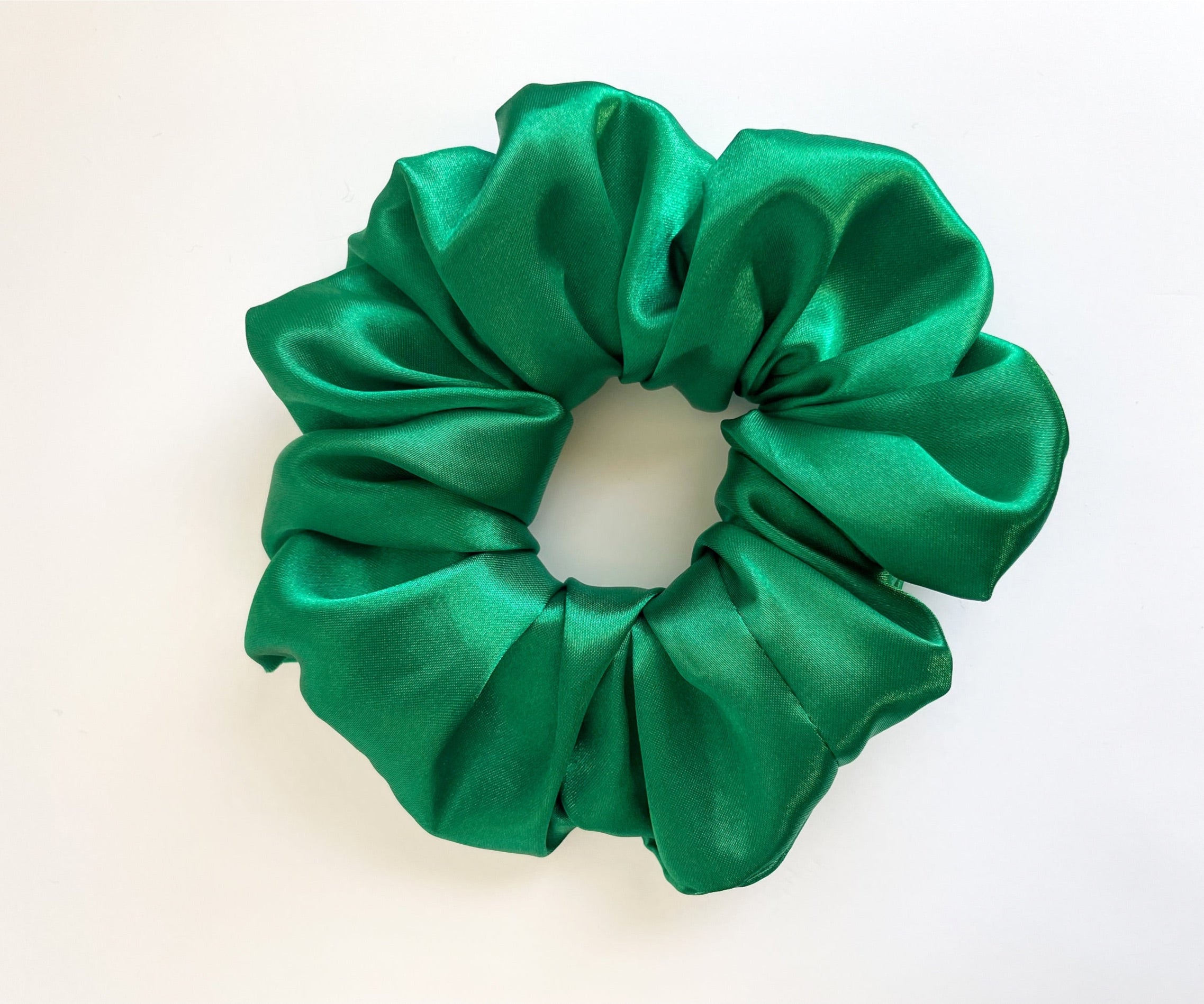 Emerald satin scrunchie with a luxurious sheen, perfect for stylish hairdos.