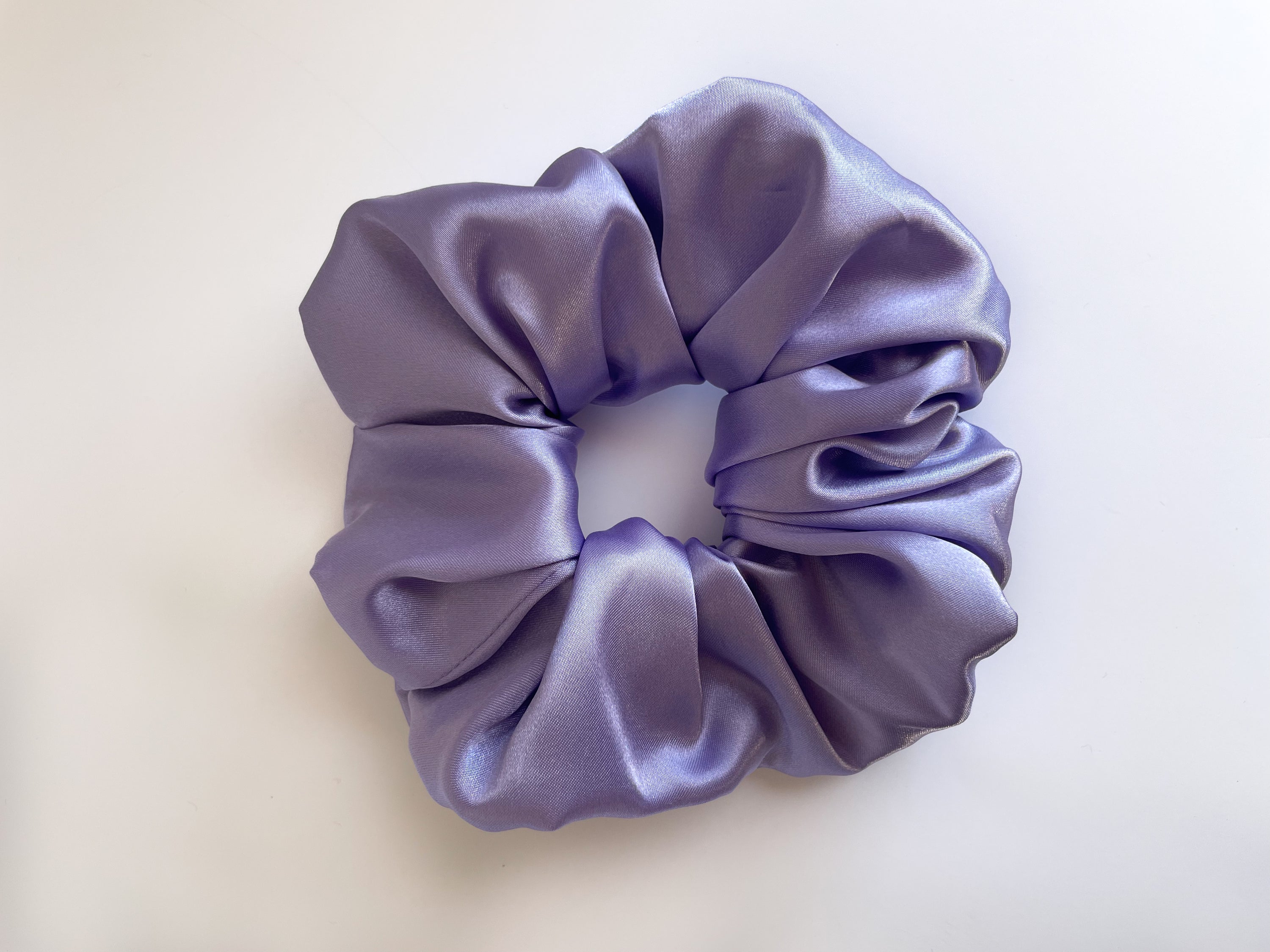 Lilac satin scrunchie elegantly displayed, showcasing its smooth texture and vibrant color.