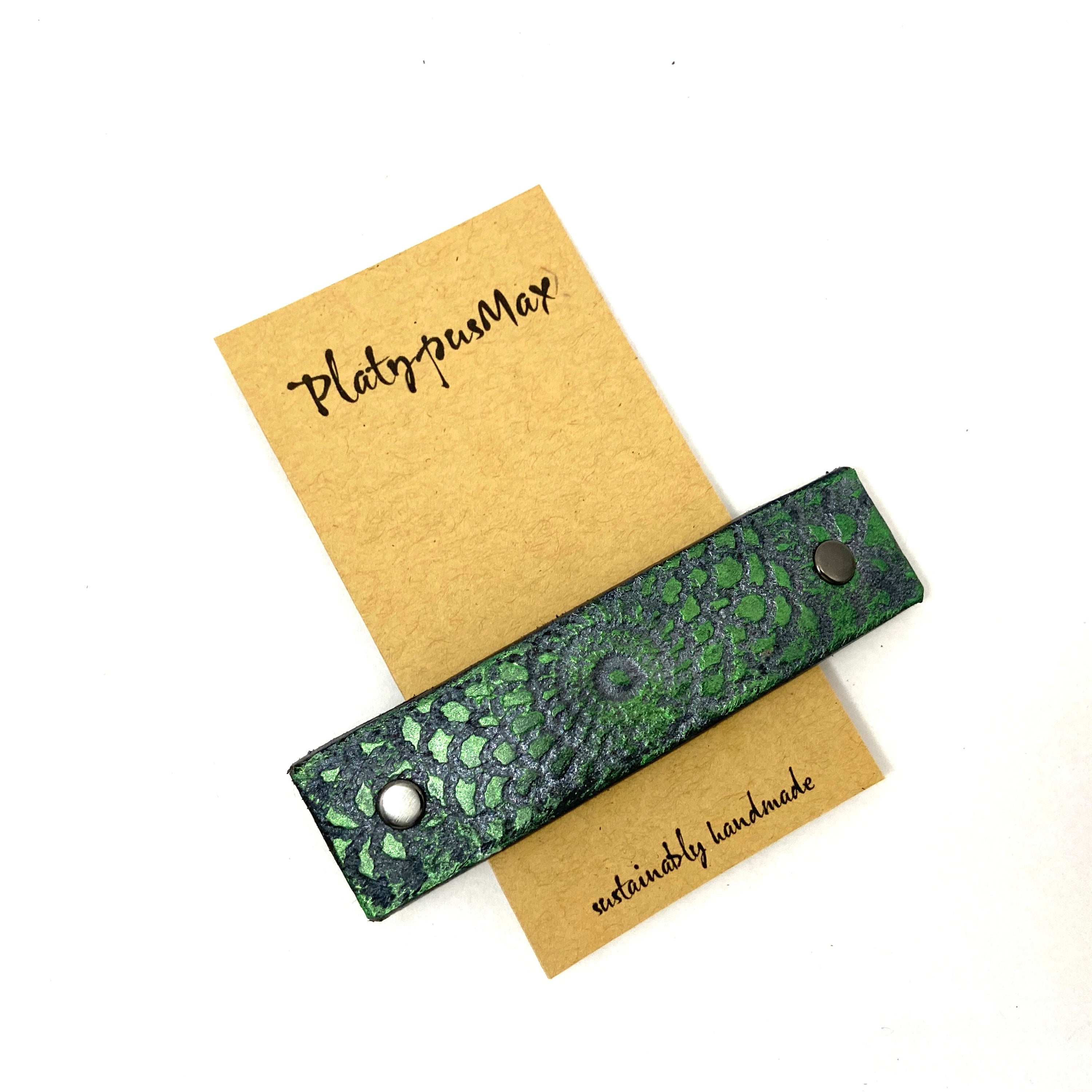 Metallic emerald green leather hair barrette with silver embossed mandala design, showcasing vintage lace texture.