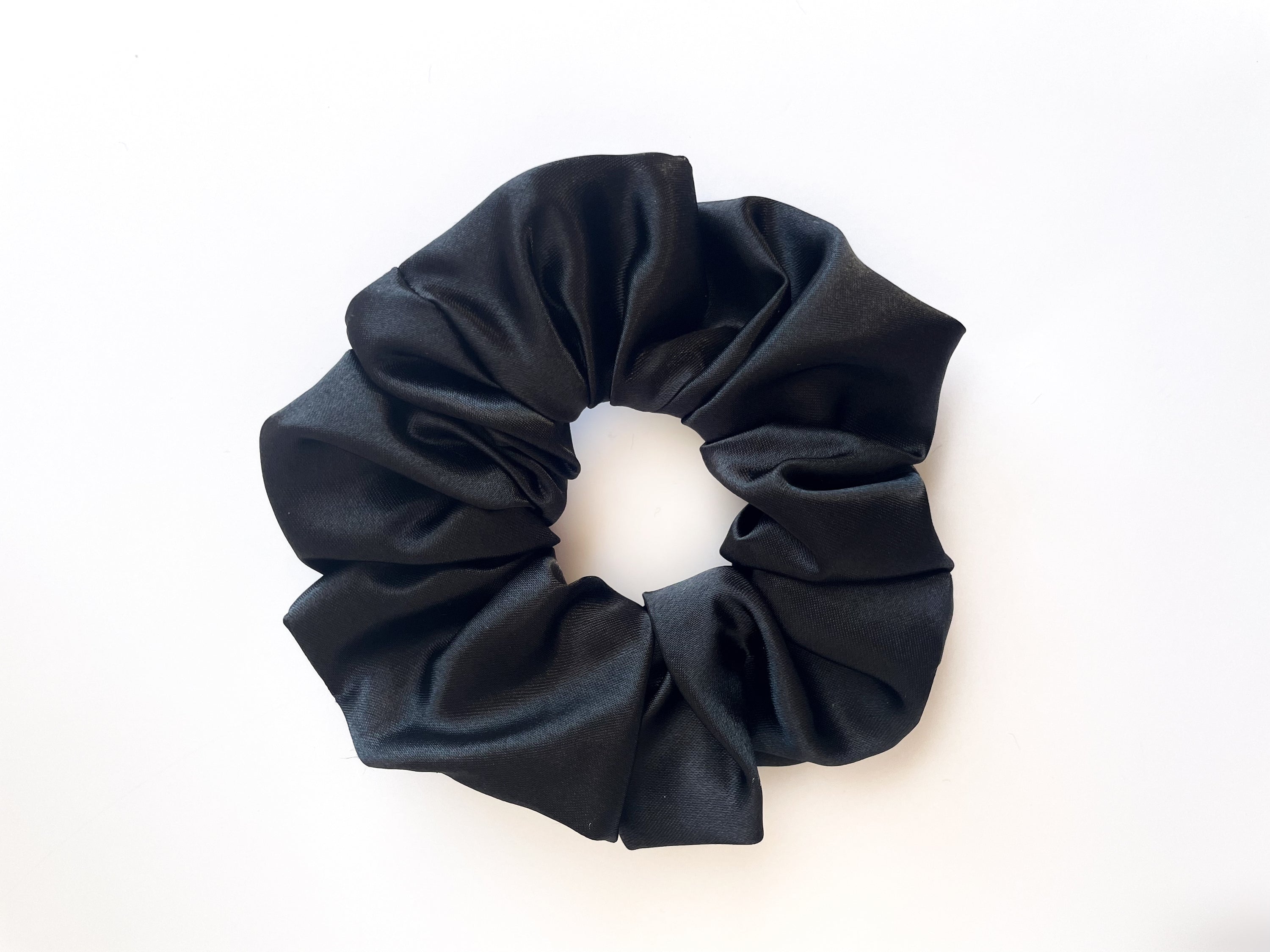 Midnight black satin scrunchie elegantly displayed, showcasing its smooth texture and luxurious appearance.