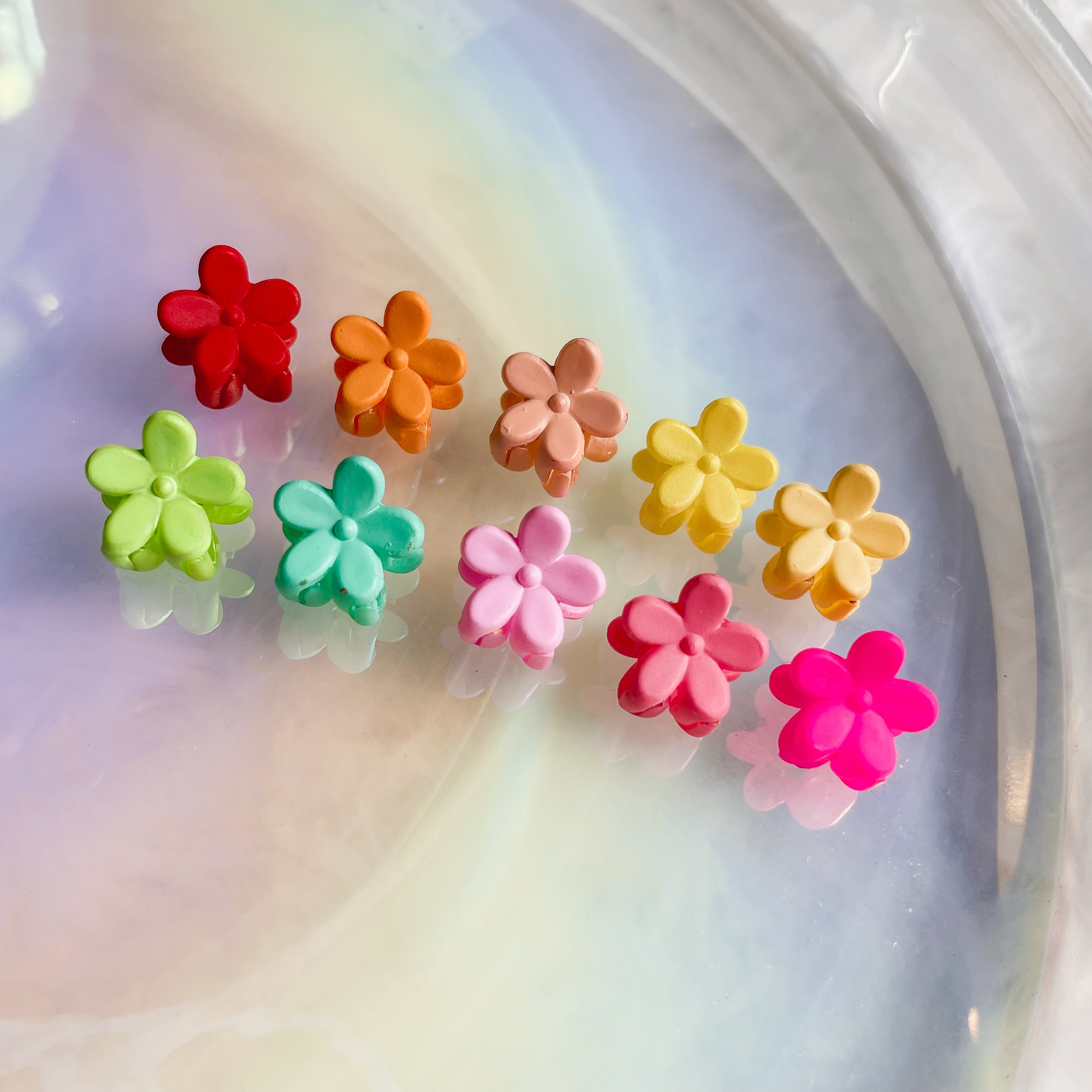 A set of ten colorful mini flower clips arranged neatly, showcasing their vibrant designs and small size, perfect for hair styling.