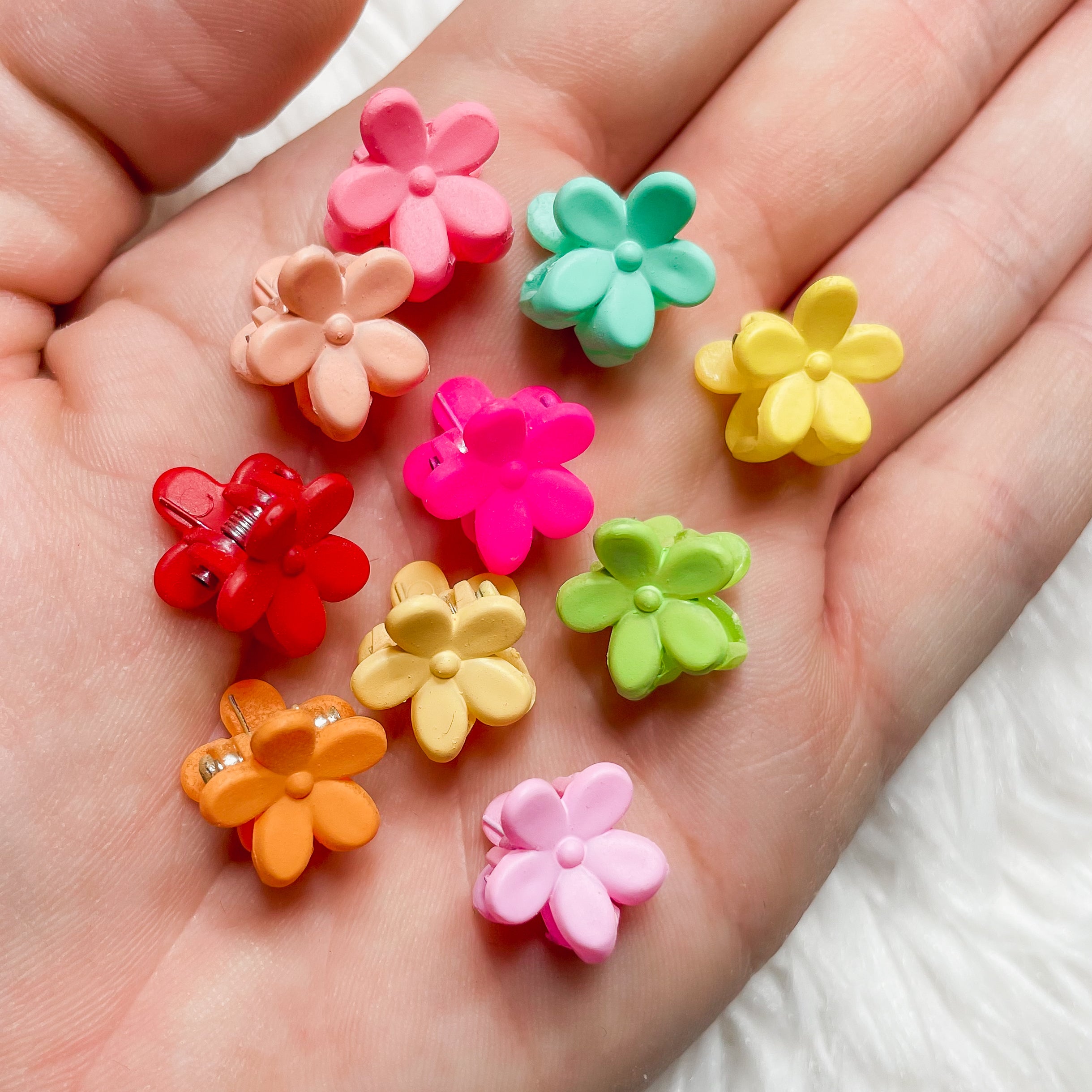 A set of ten colorful mini flower clips arranged neatly, showcasing their vibrant designs and small size, perfect for hair styling.