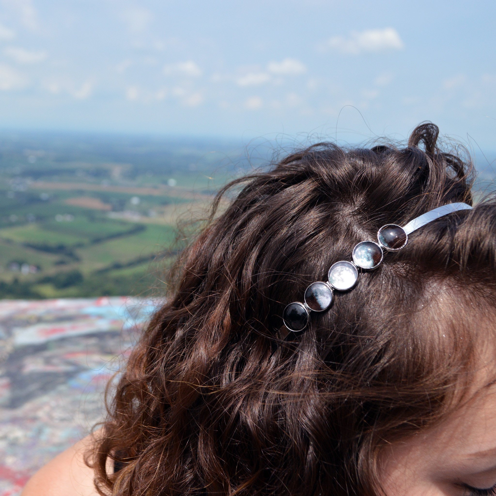 A beautiful Moon Phase Headband featuring five distinct lunar phases in shiny silver and gold tones, handcrafted with rhodium plated brass and glass.