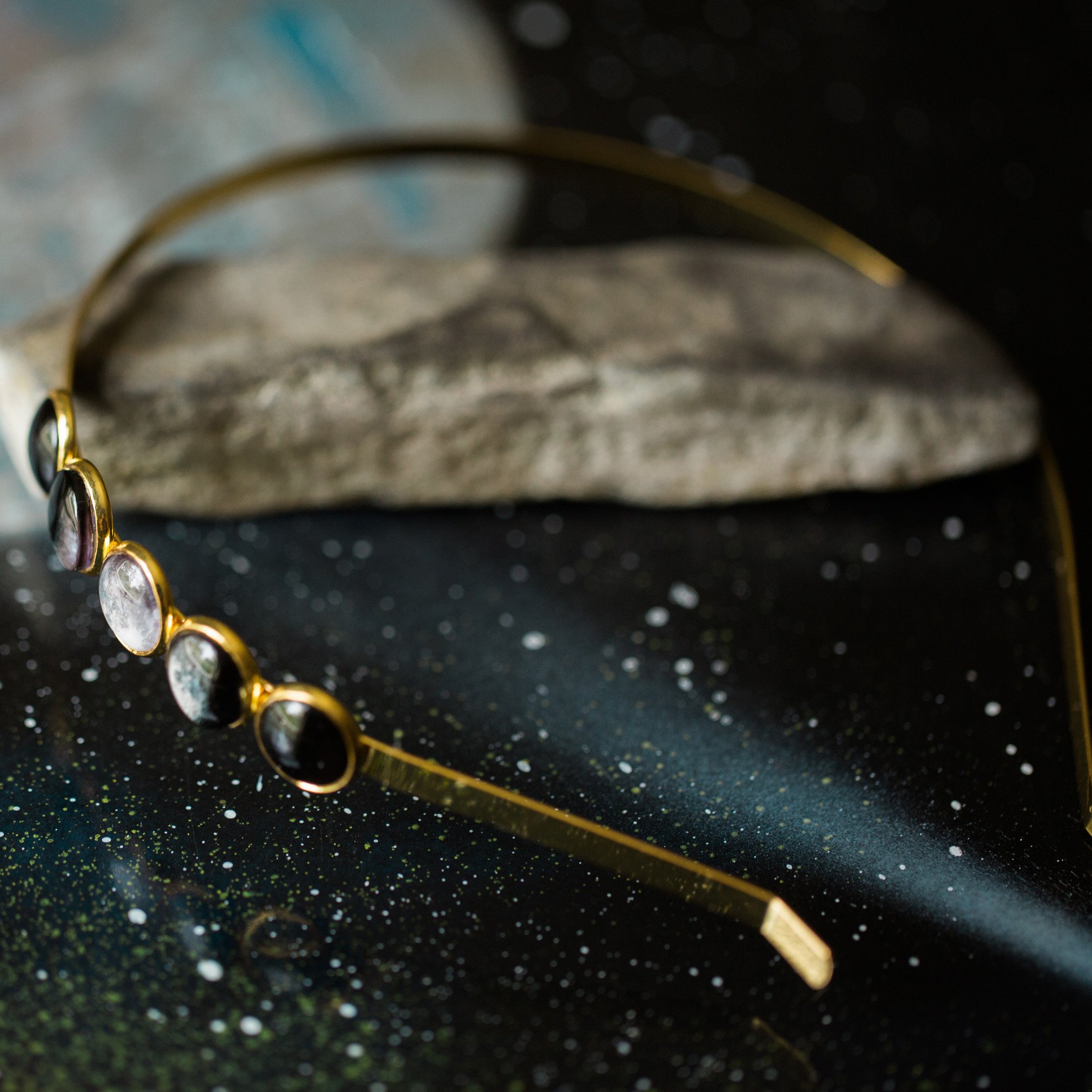 A beautiful Moon Phase Headband featuring five distinct lunar phases in shiny silver and gold tones, handcrafted with rhodium plated brass and glass.