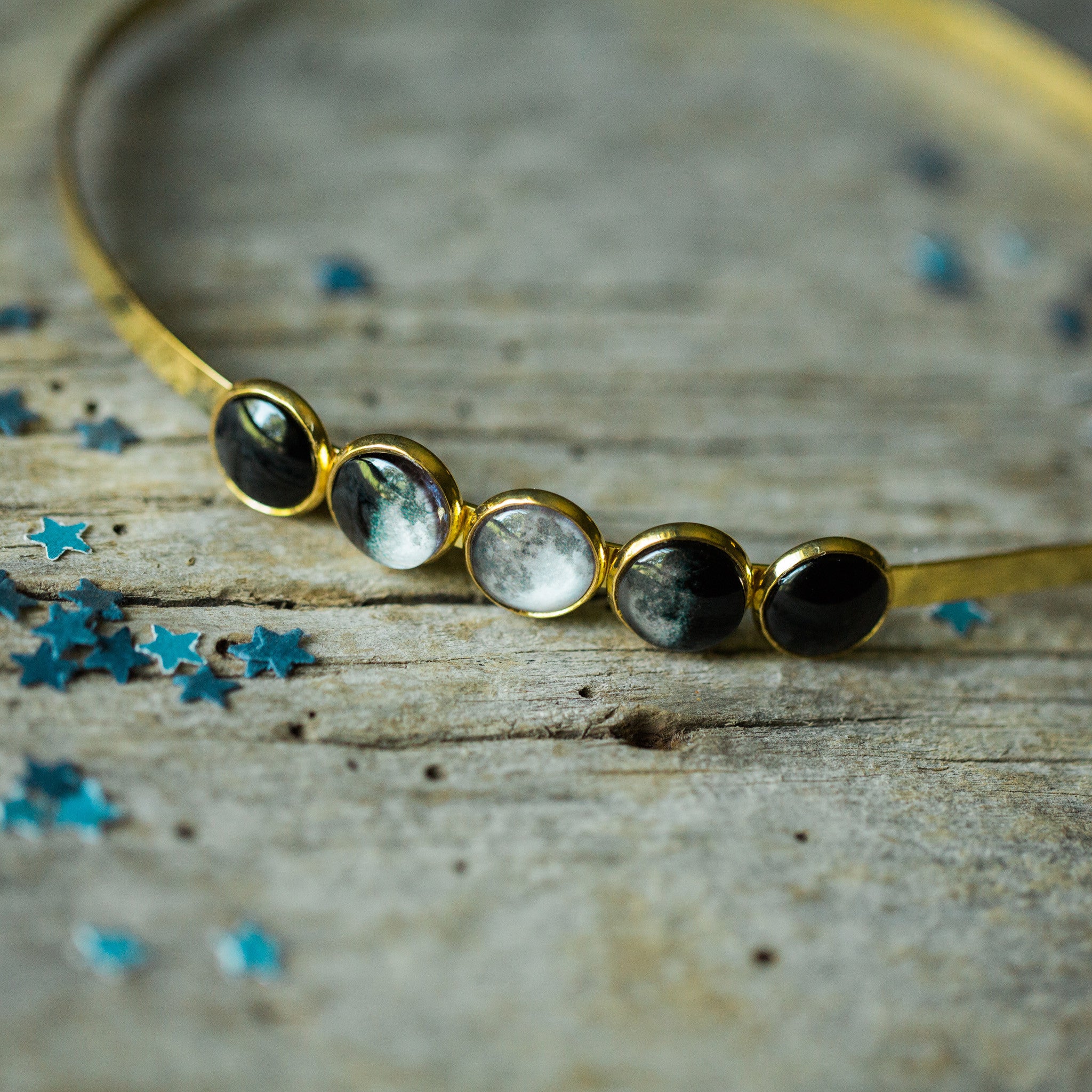 A beautiful Moon Phase Headband featuring five distinct lunar phases in shiny silver and gold tones, handcrafted with rhodium plated brass and glass.