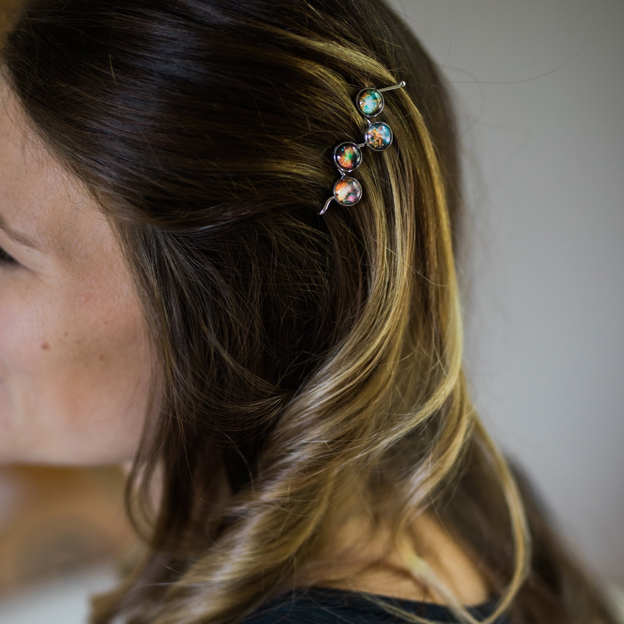 Nebula Hair Clip featuring vibrant galaxy images of Omega, Dumbbell, Carina, and Crab Nebula, handcrafted with rhodium plated brass.