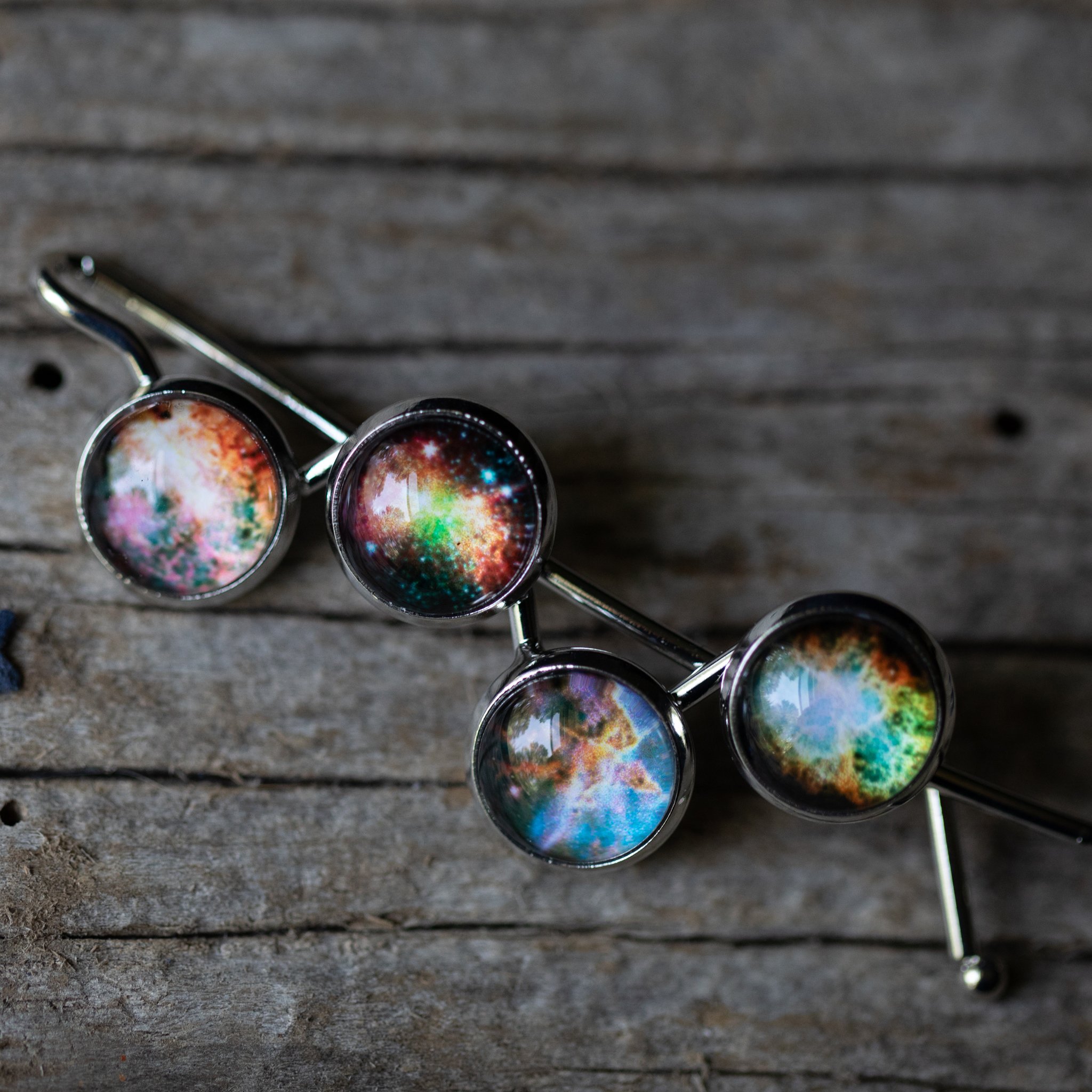 Nebula Hair Clip featuring vibrant galaxy images of Omega, Dumbbell, Carina, and Crab Nebula, handcrafted with rhodium plated brass.