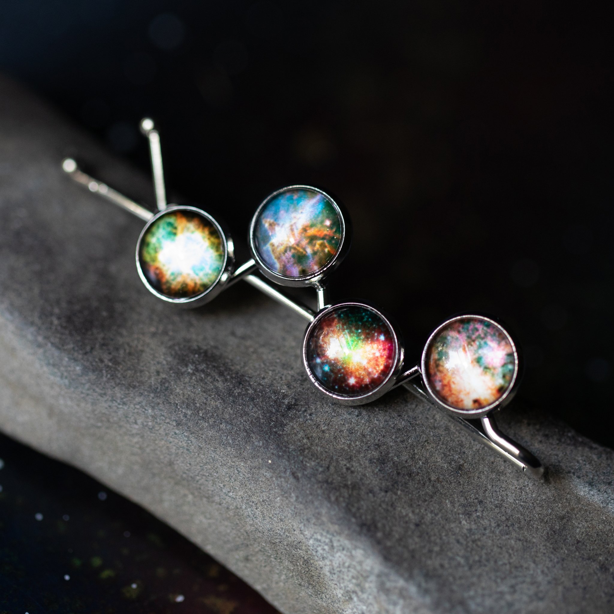 Nebula Hair Clip featuring vibrant galaxy images of Omega, Dumbbell, Carina, and Crab Nebula, handcrafted with rhodium plated brass.