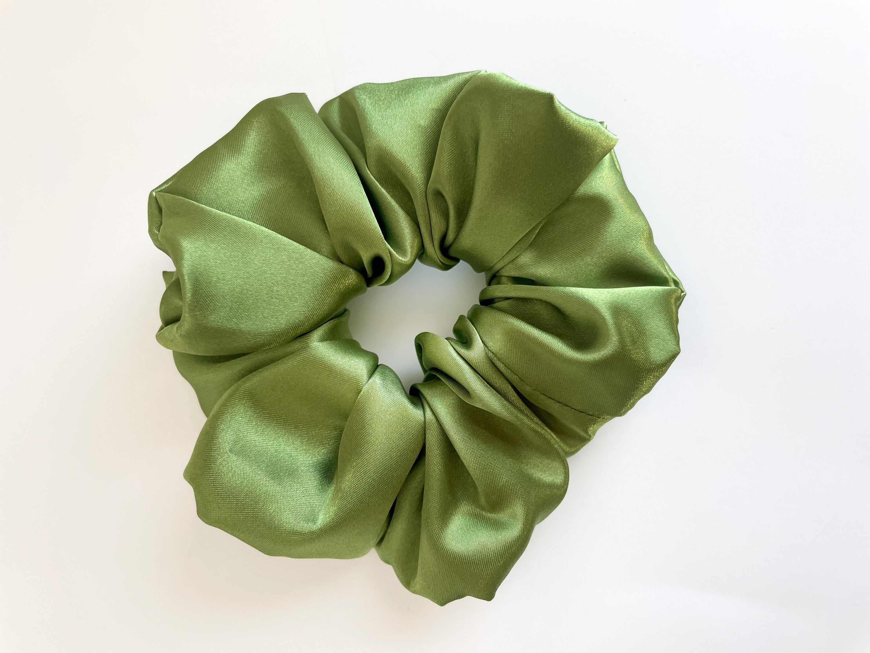 Olive satin scrunchie with a smooth texture, perfect for stylish hairstyles.