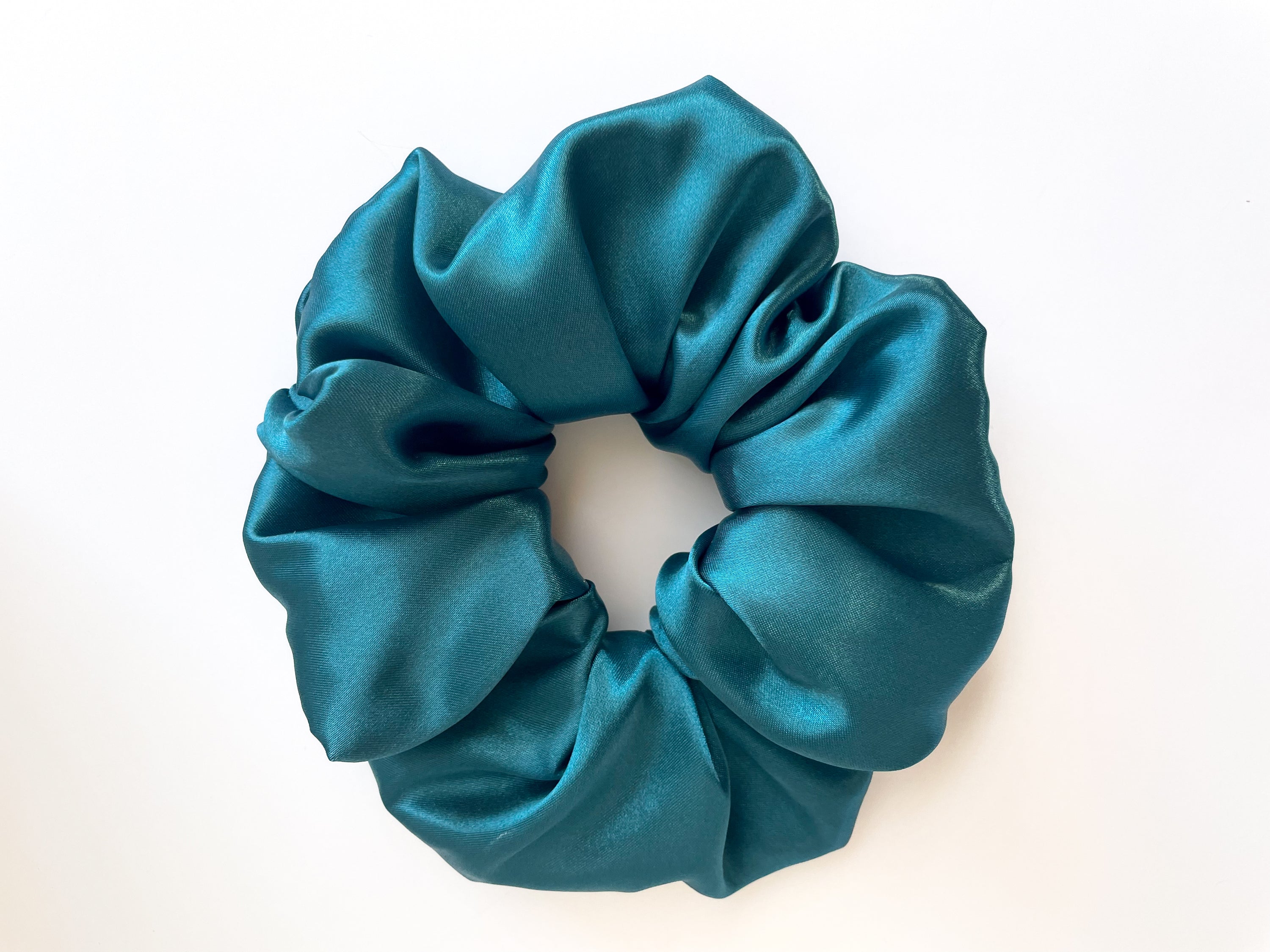 A luxurious sapphire satin scrunchie, elegantly styled and perfect for all hair types.