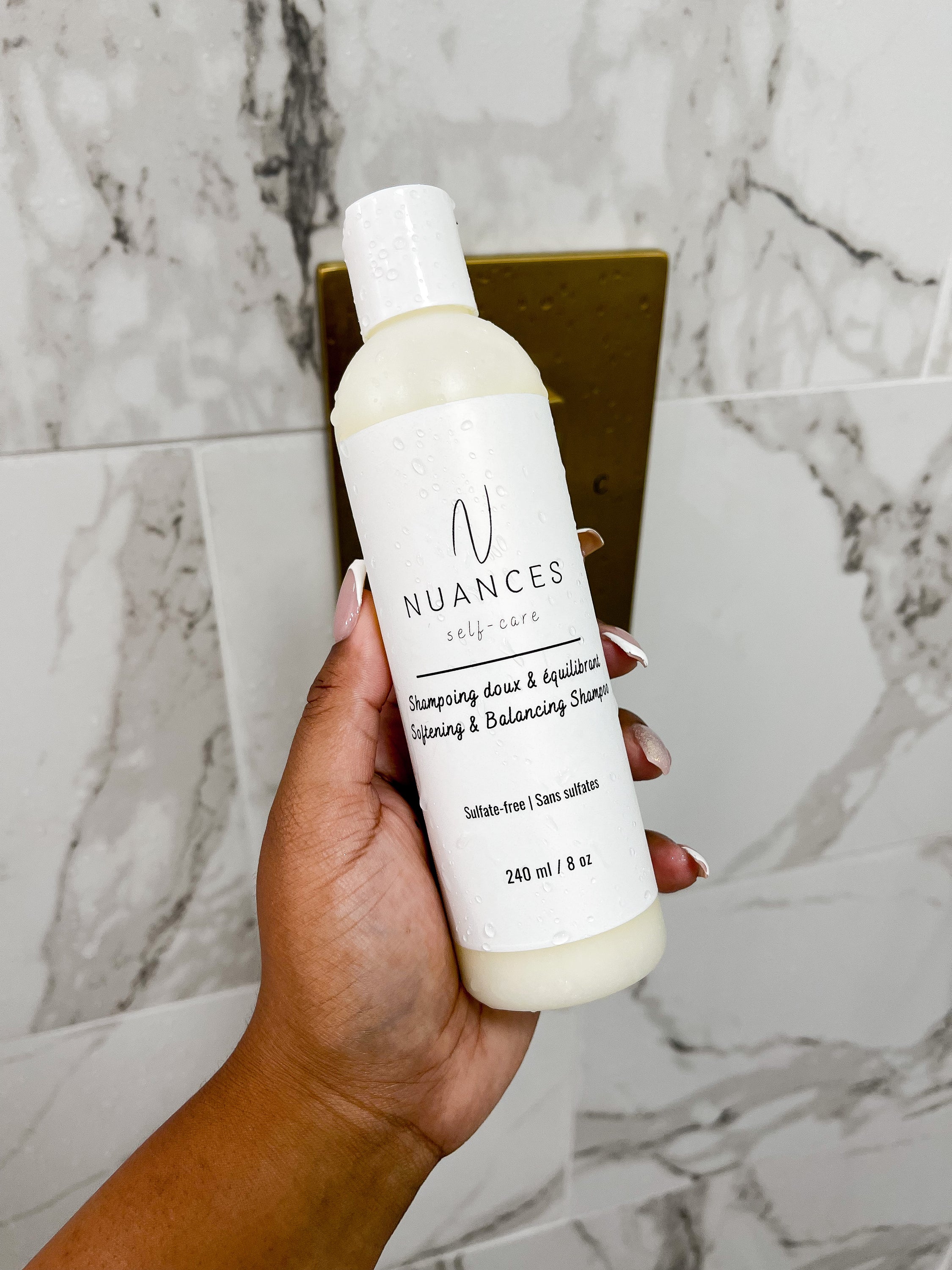 A bottle of Softening & Balancing Shampoo with a fresh and clean design, featuring natural ingredients like aloe vera and coconut oil.