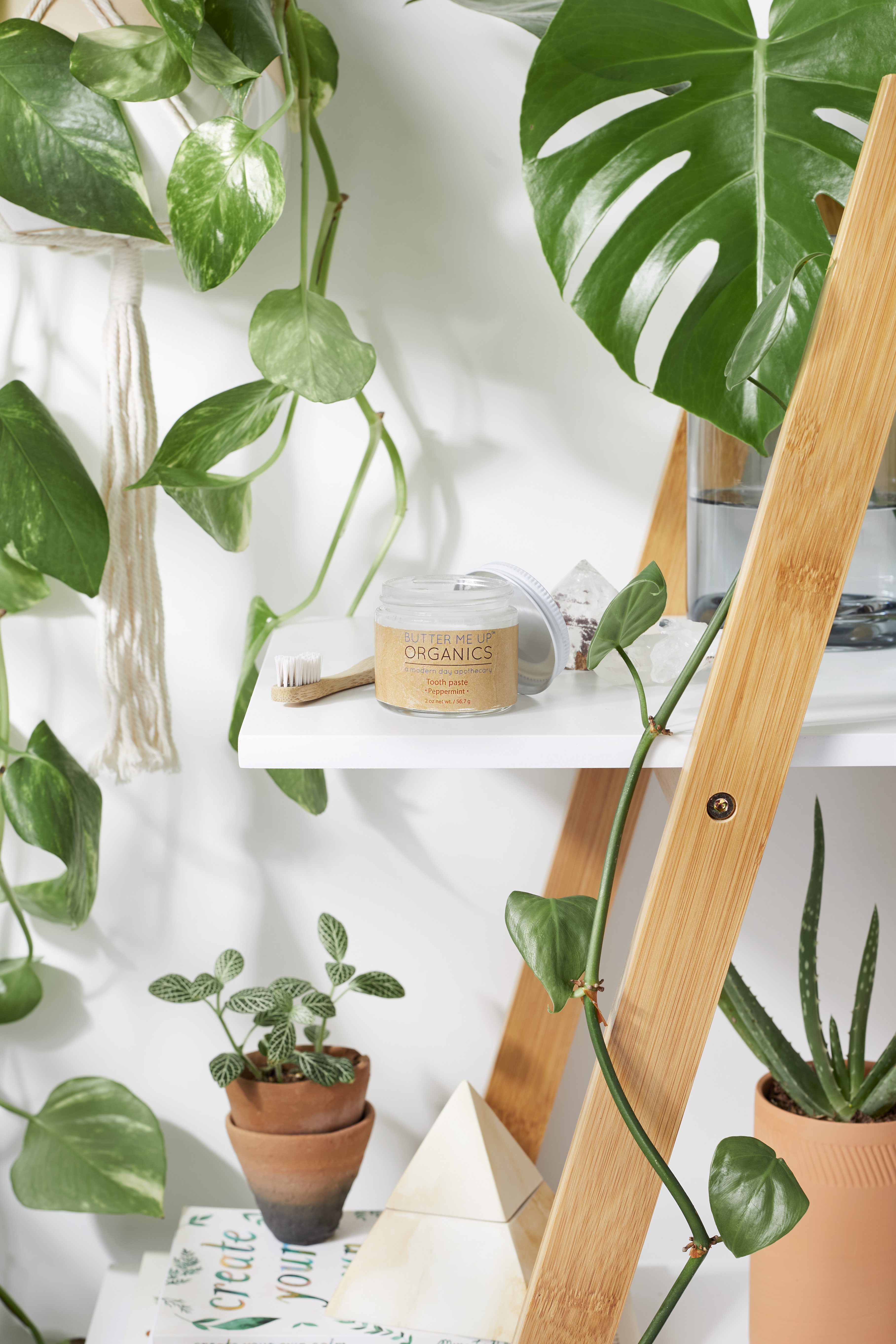 A glass jar of All Natural Organic Whitening Toothpaste with a wooden applicator, showcasing its creamy texture and natural ingredients.