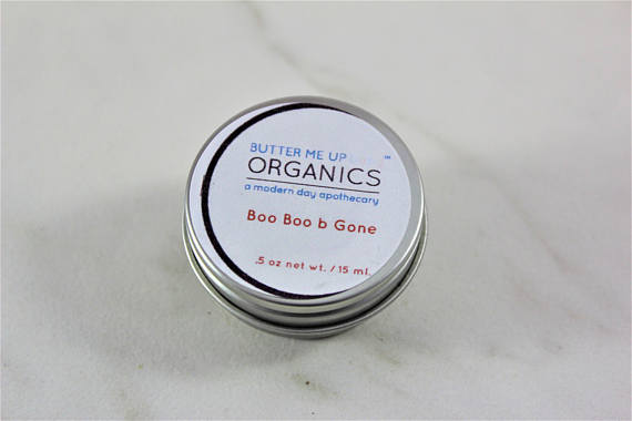 A small tin of Boo Boo b Gone natural neosporin salve, featuring a blend of organic herbal oils for healing cuts and scrapes, with a rustic design.