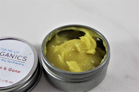 A small tin of Boo Boo b Gone natural neosporin salve, featuring a blend of organic herbal oils for healing cuts and scrapes, with a rustic design.