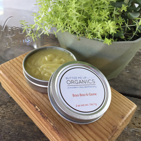 A small tin of Boo Boo b Gone natural neosporin salve, featuring a blend of organic herbal oils for healing cuts and scrapes, with a rustic design.