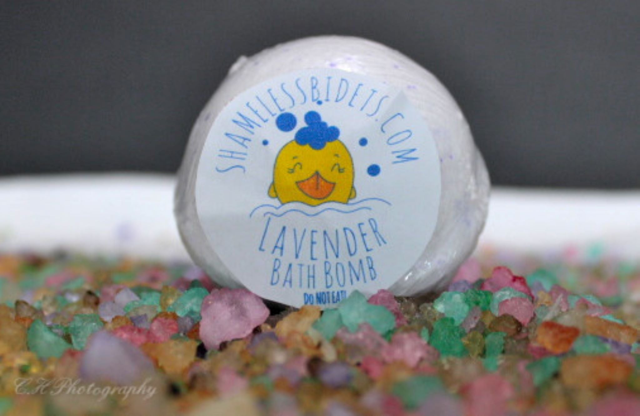 Lavender bath bomb on colorful rocks.