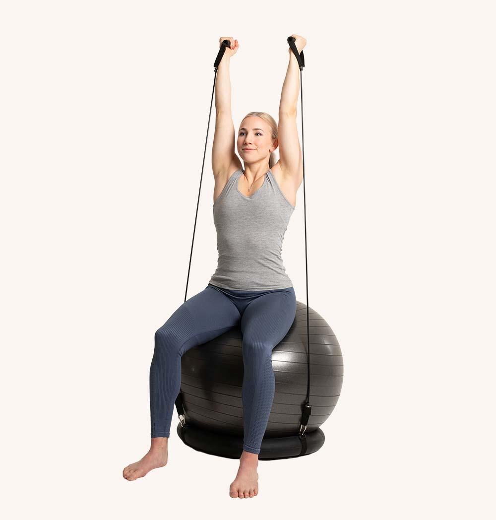 A vibrant Pilates ball with attached resistance bands, ideal for yoga and fitness exercises, placed on a gym mat.