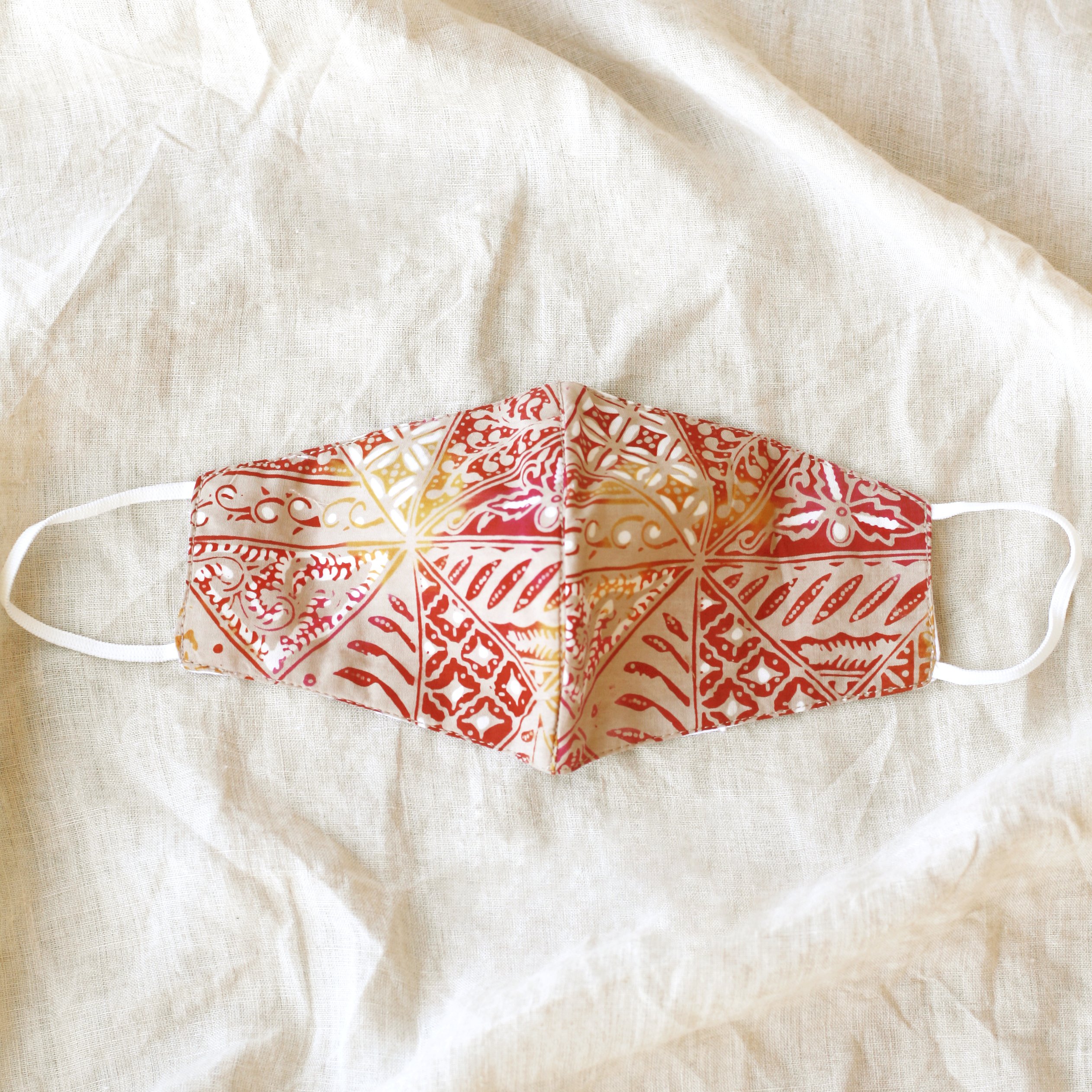 A vibrant RED JAVA Triple Layer Vintage Batik Face Mask featuring intricate patterns, made from traditional hand-stamped Batik fabric, with a waterproof filter included.