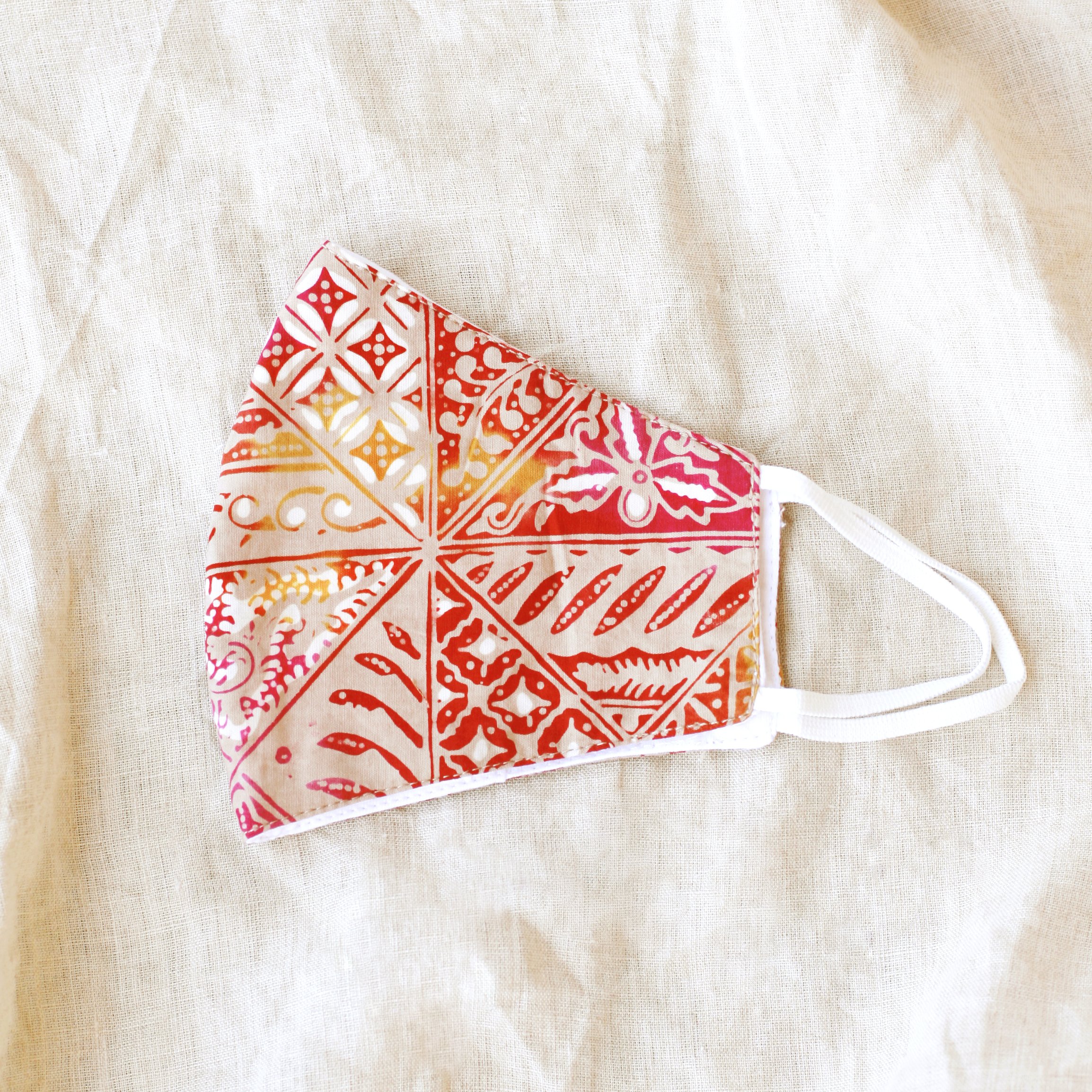 A vibrant RED JAVA Triple Layer Vintage Batik Face Mask featuring intricate patterns, made from traditional hand-stamped Batik fabric, with a waterproof filter included.