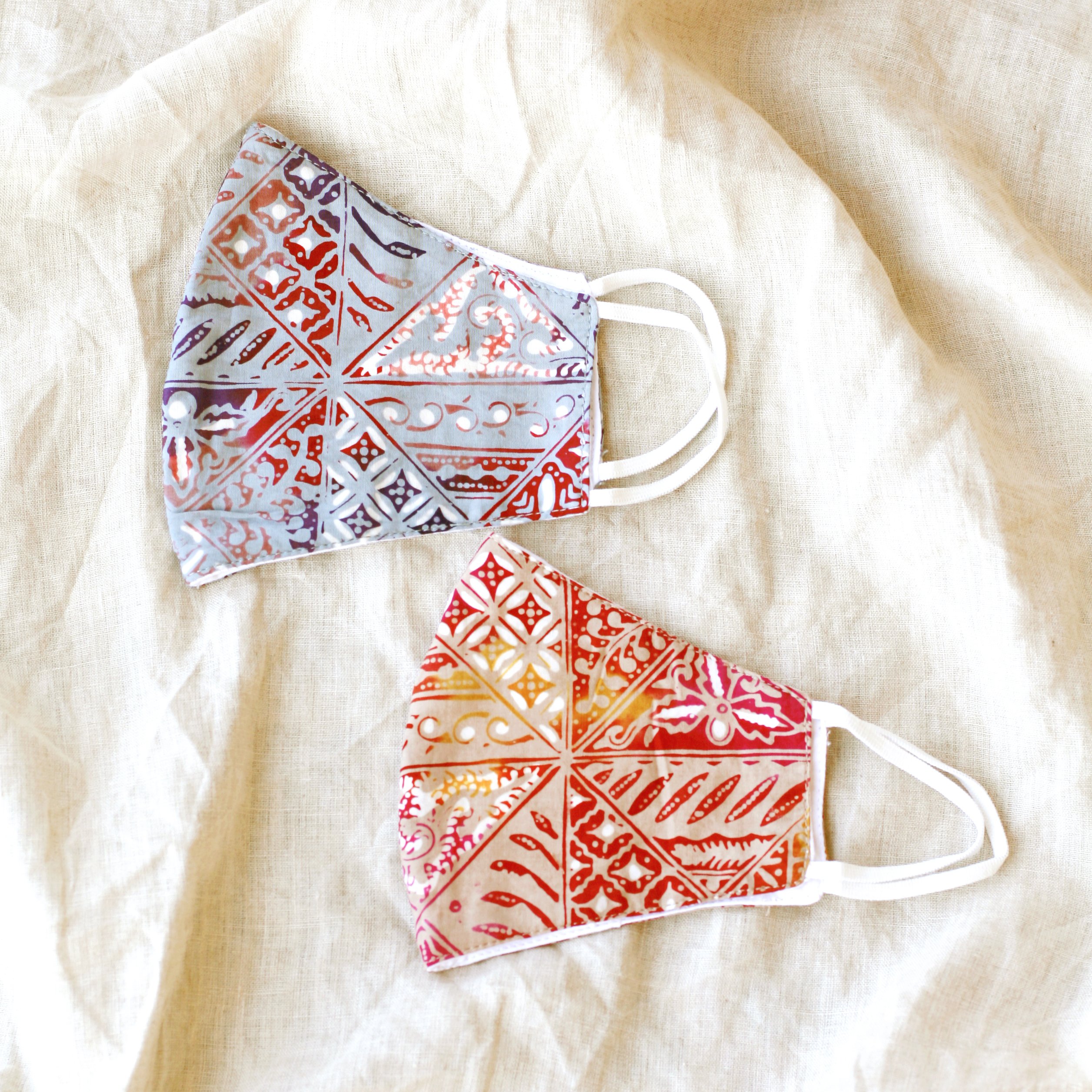 A vibrant RED JAVA Triple Layer Vintage Batik Face Mask featuring intricate patterns, made from traditional hand-stamped Batik fabric, with a waterproof filter included.