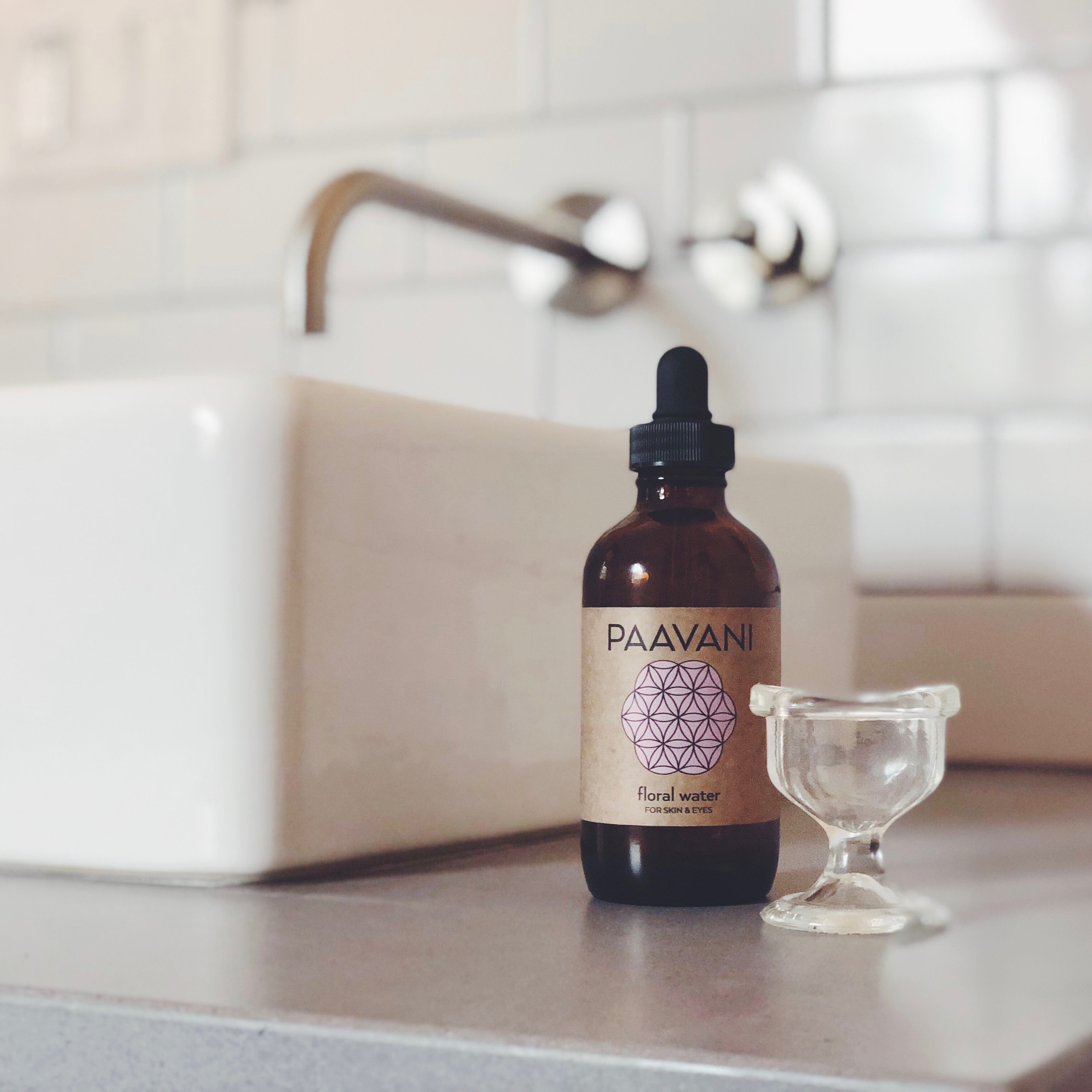 A soothing eye wash ritual kit featuring floral water, a glass eye wash cup, and a muslin travel pouch, designed for eye health and rejuvenation.