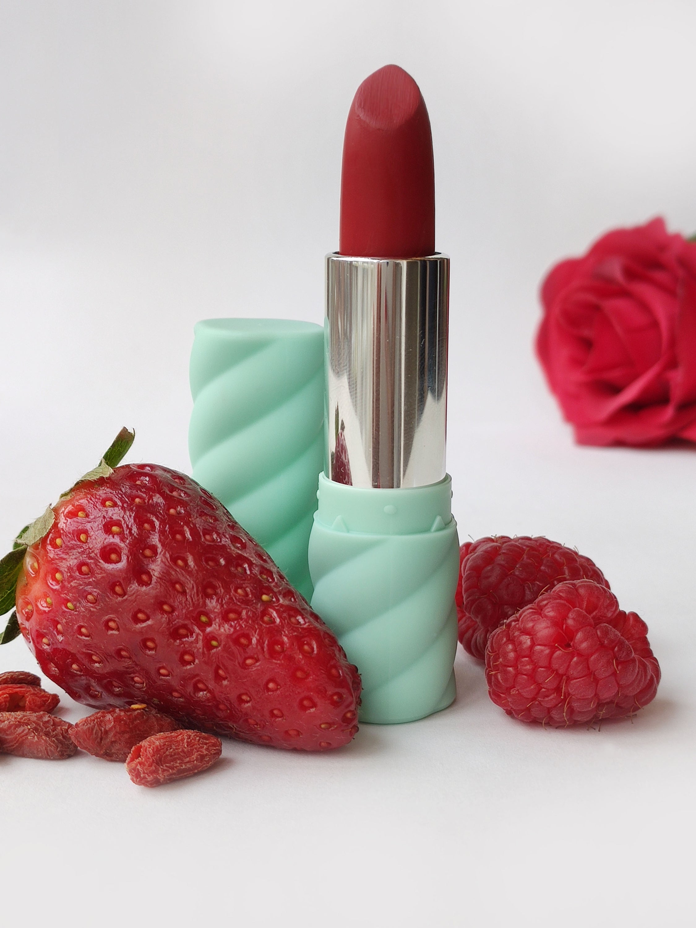 04 Rossetto 'It's Hot in Colorland' lipstick showcasing a vibrant red shade with a creamy texture, surrounded by fruit-inspired elements.