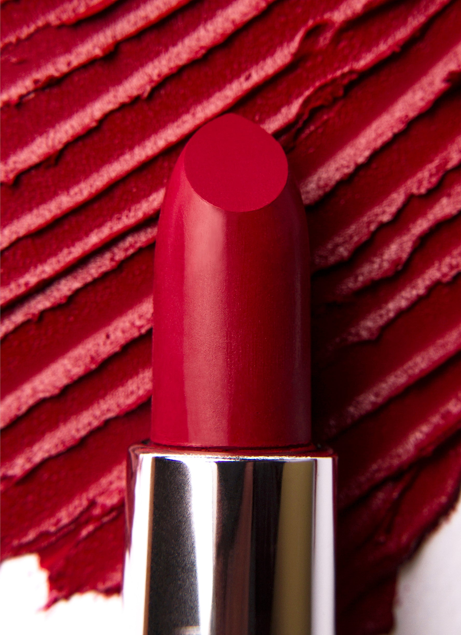 04 Rossetto 'It's Hot in Colorland' lipstick showcasing a vibrant red shade with a creamy texture, surrounded by fruit-inspired elements.