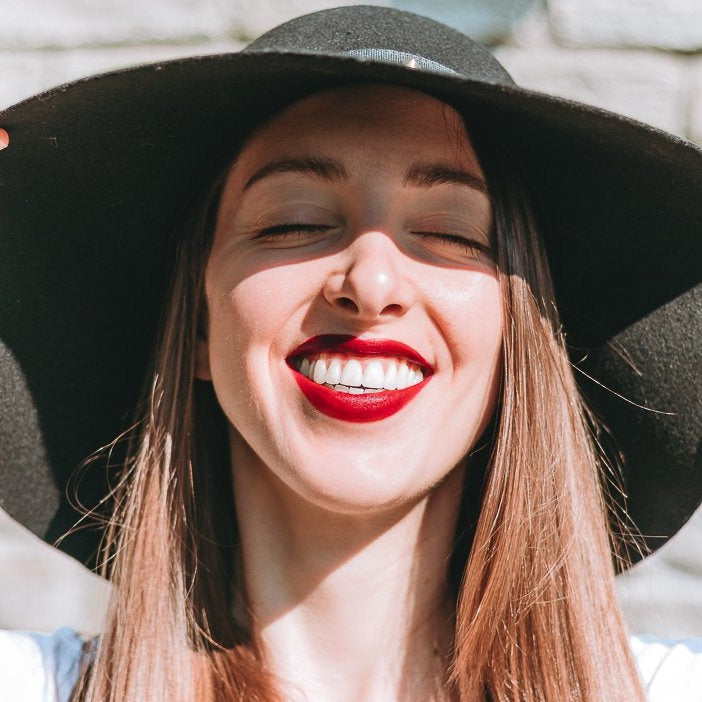 04 Rossetto 'It's Hot in Colorland' lipstick showcasing a vibrant red shade with a creamy texture, surrounded by fruit-inspired elements.