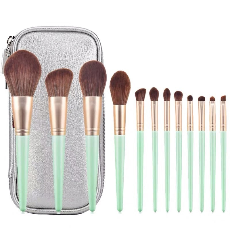 A set of 12 makeup brushes with soft bristles and wooden handles in green and white colors, ideal for foundation and eye shadow application.