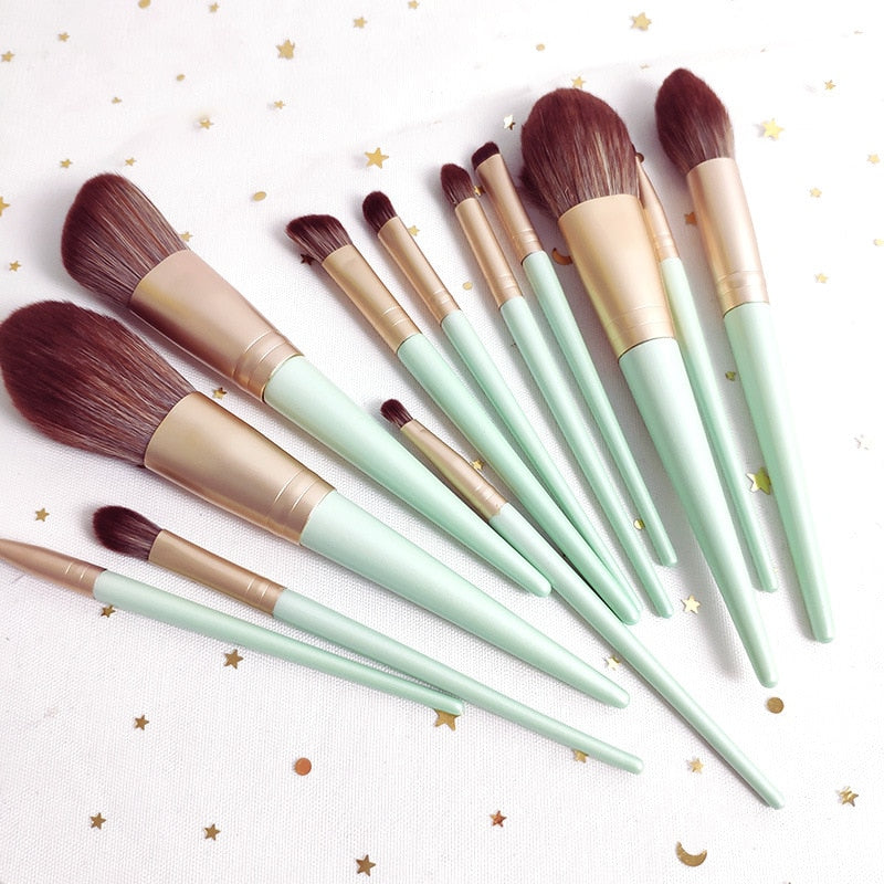 A set of 12 makeup brushes with soft bristles and wooden handles in green and white colors, ideal for foundation and eye shadow application.