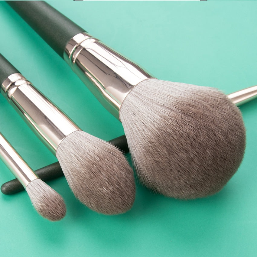 14-piece Green Cloud Makeup Brushes Set with wooden handles and nylon bristles, neatly arranged in a leather bag.