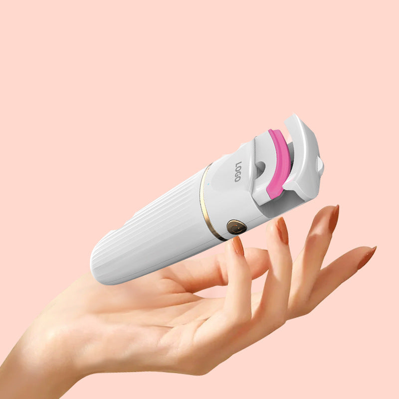 Electric eyelash curler in white, pink, and blue colors, showcasing its sleek design and compact size.