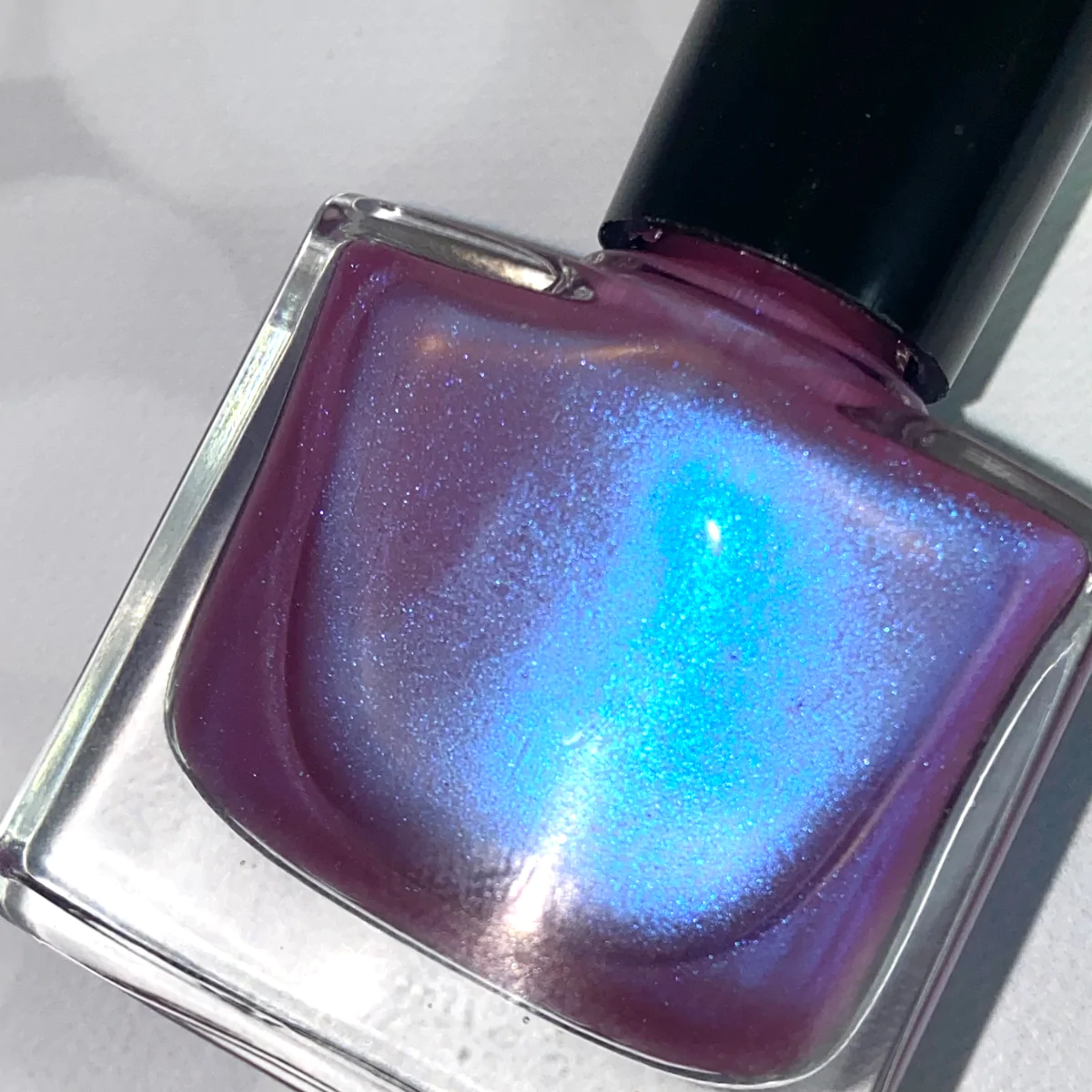 Bottle of Extraterrestrial Diamond Nail Polish showcasing its triple chrome effect with shifts of pink, blue, and red.