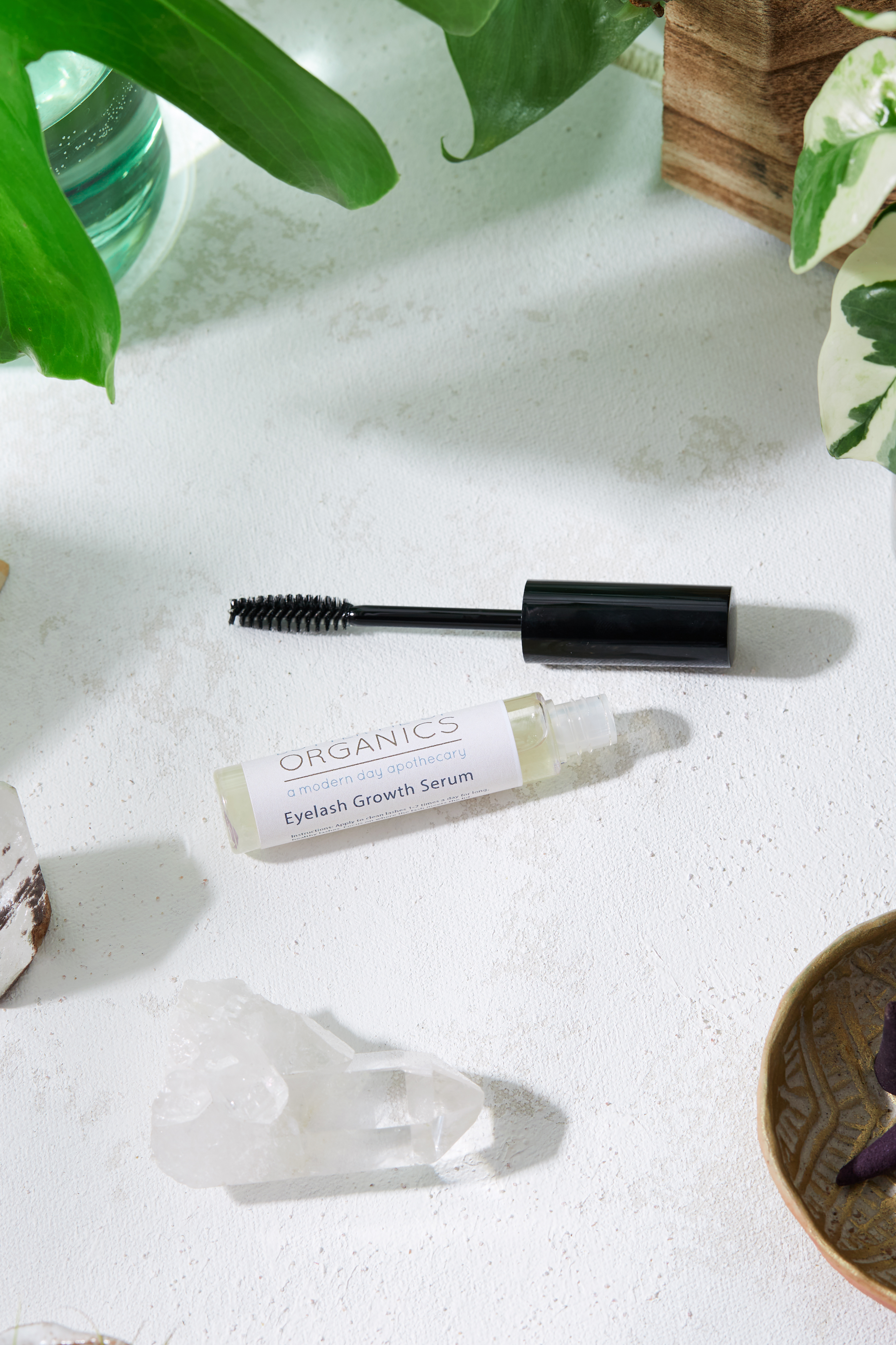 A bottle of organic eyelash growth serum with a brush applicator, set against a soft, natural background, showcasing its eco-friendly packaging.