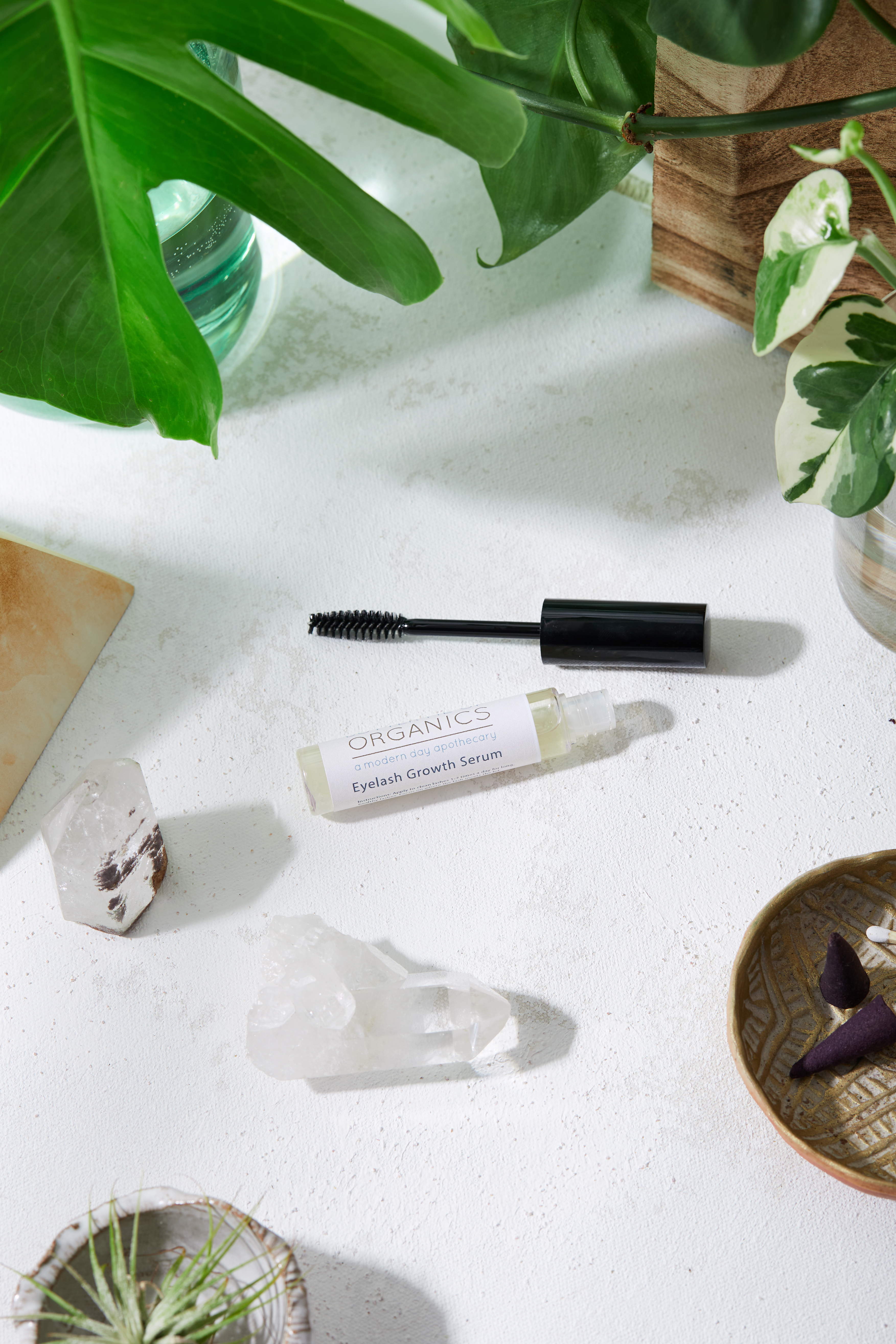 A bottle of organic eyelash growth serum with a brush applicator, set against a soft, natural background, showcasing its eco-friendly packaging.