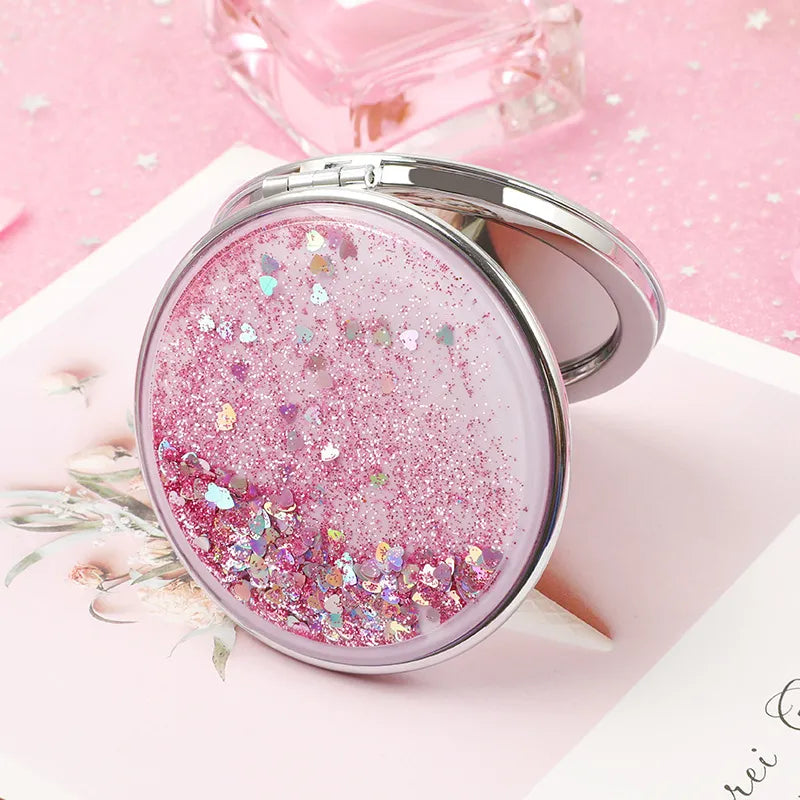 A stylish double-sided portable mirror featuring glitter quicksand design, showcasing both 1x and 2x magnification options.