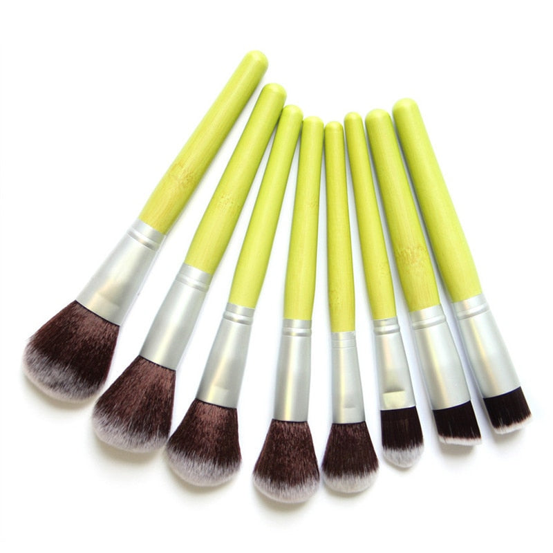 A complete set of 23 eco-friendly green bamboo makeup brushes with black to white tipped nylon bristles, elegantly displayed.