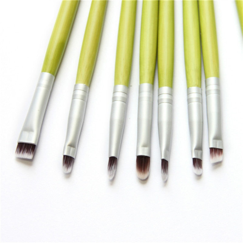 A complete set of 23 eco-friendly green bamboo makeup brushes with black to white tipped nylon bristles, elegantly displayed.