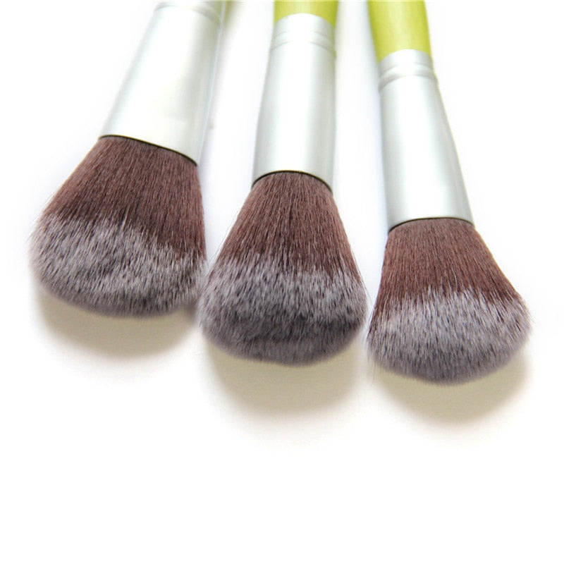 A complete set of 23 eco-friendly green bamboo makeup brushes with black to white tipped nylon bristles, elegantly displayed.